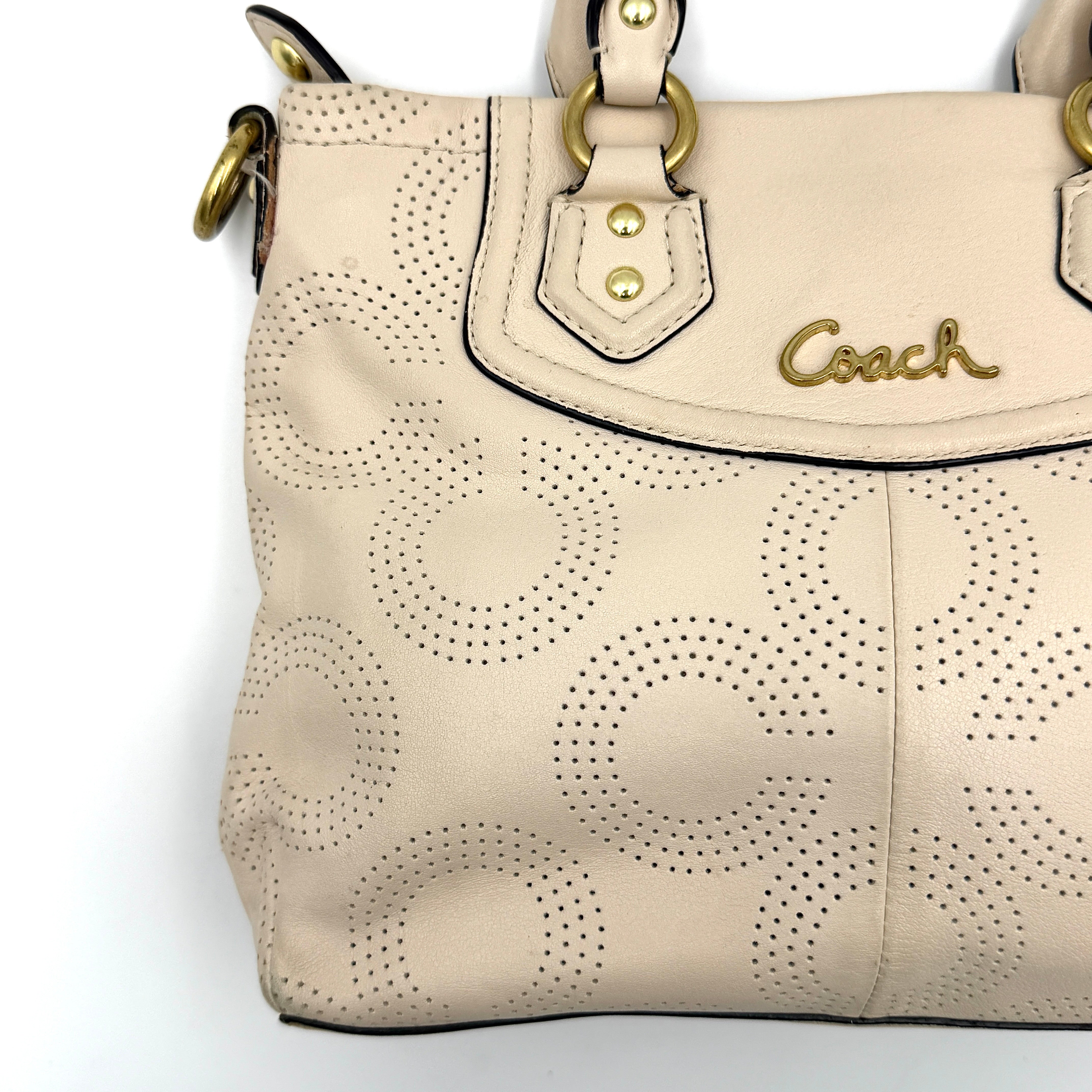 Coach Ashley 2Way cream perforated Op Art leather handbag with dual handles and detachable strap, styled on a white background.