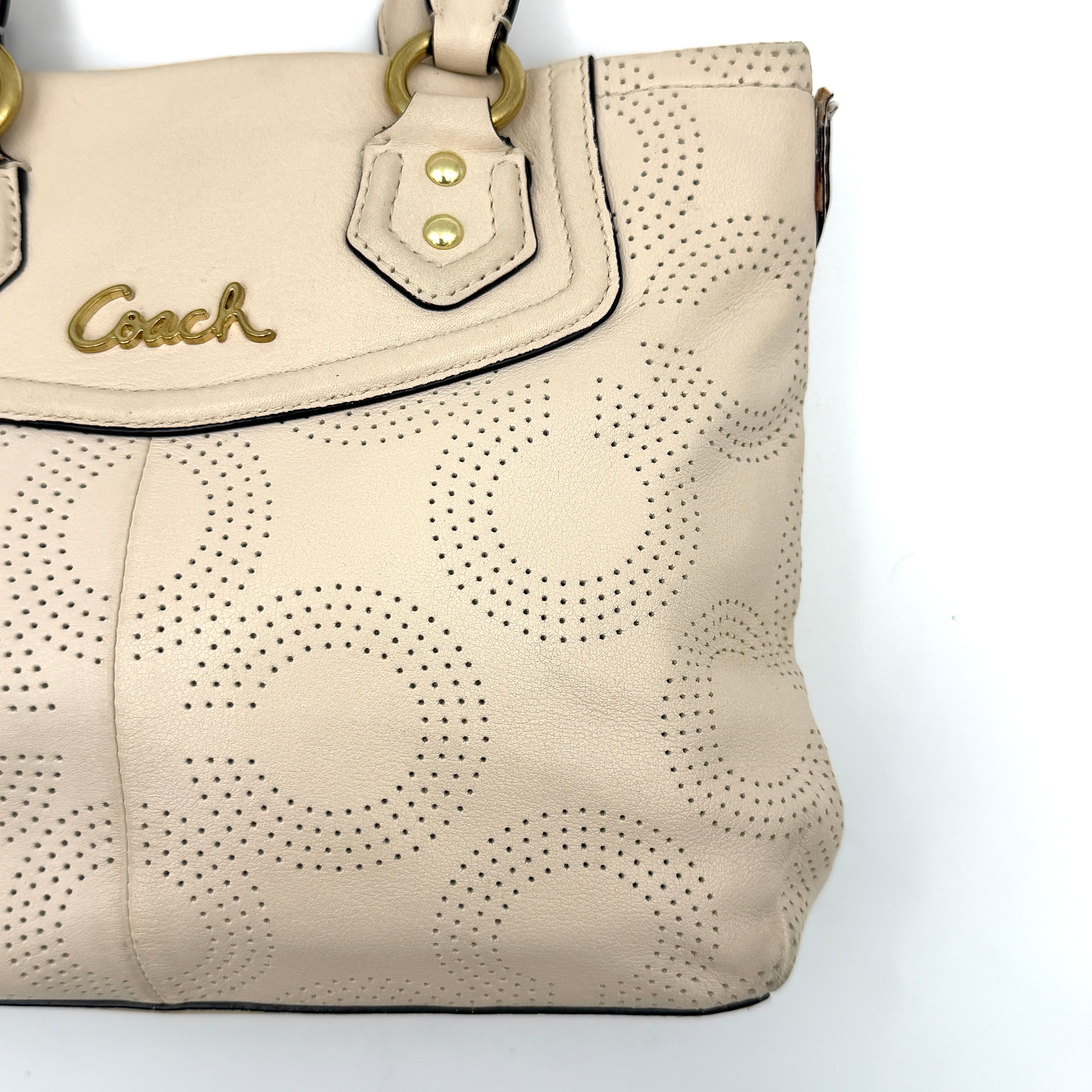 Coach Ashley 2Way cream perforated Op Art leather handbag with dual handles and detachable strap, styled on a white background.