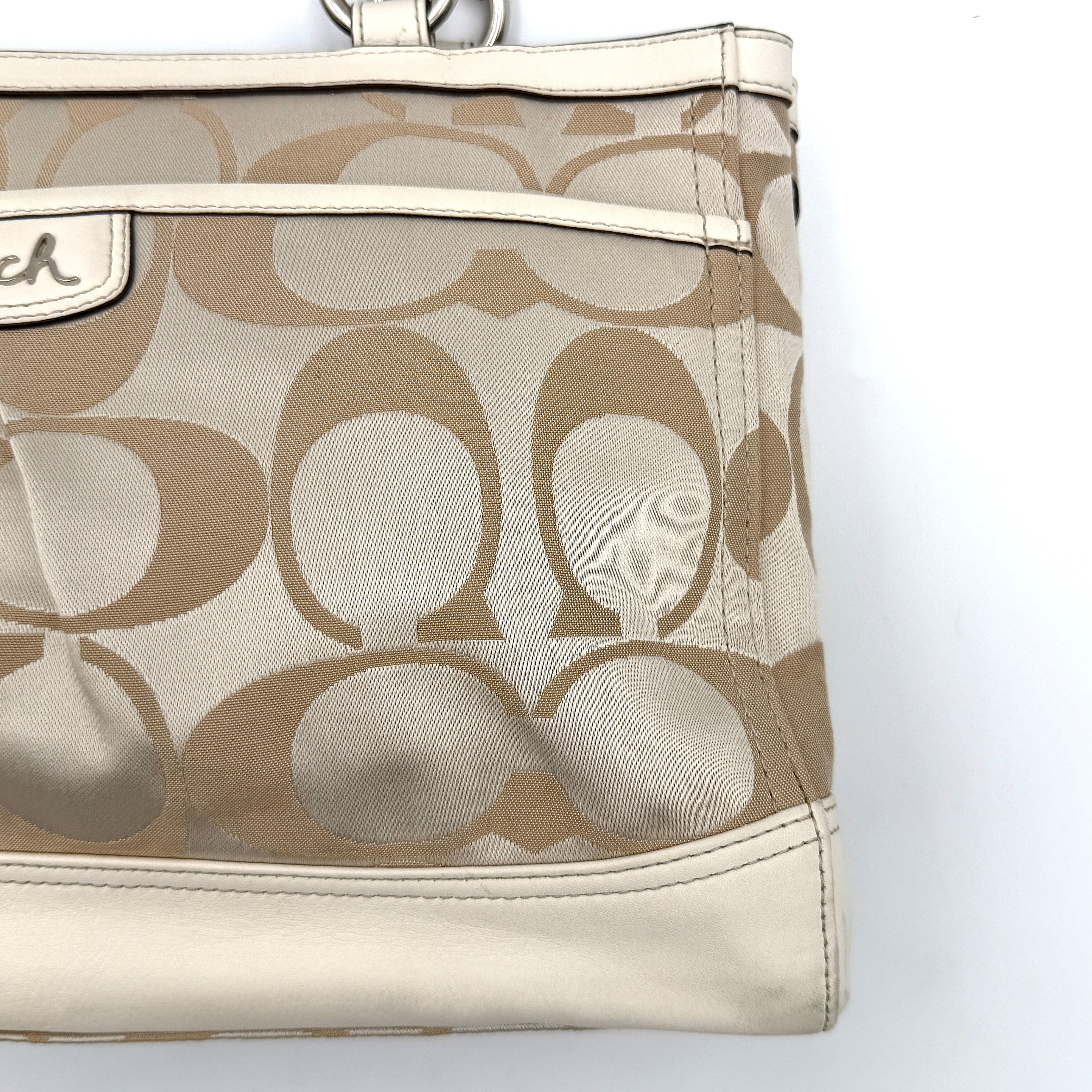 Coach Signature Carryall Shoulder Bag in beige jacquard canvas with cream leather trim and silver hardware displayed against a white background.