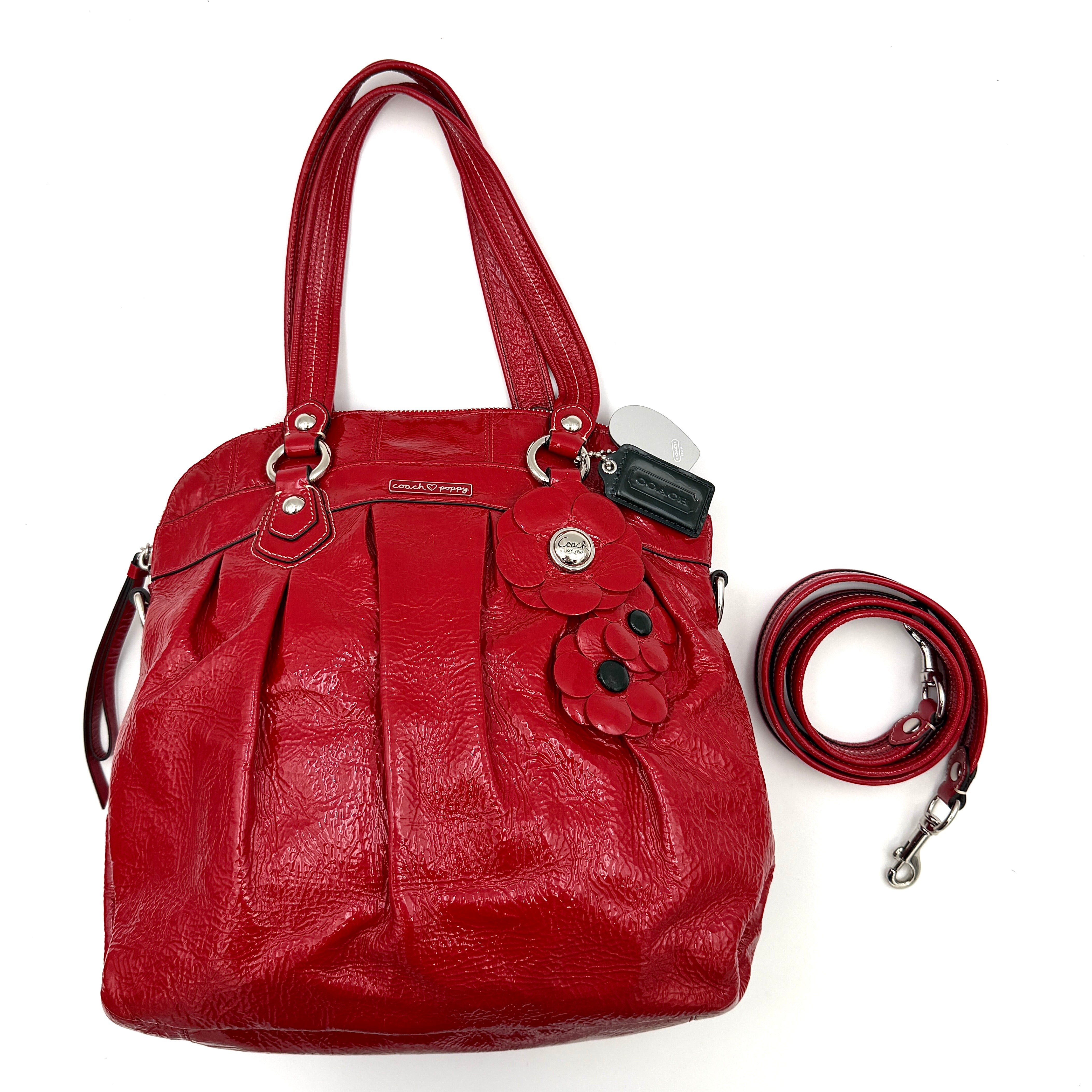 Coach Poppy 2Way shoulder bag in glossy red patent leather with floral appliqué, heart charm, double handles and detachable long strap.