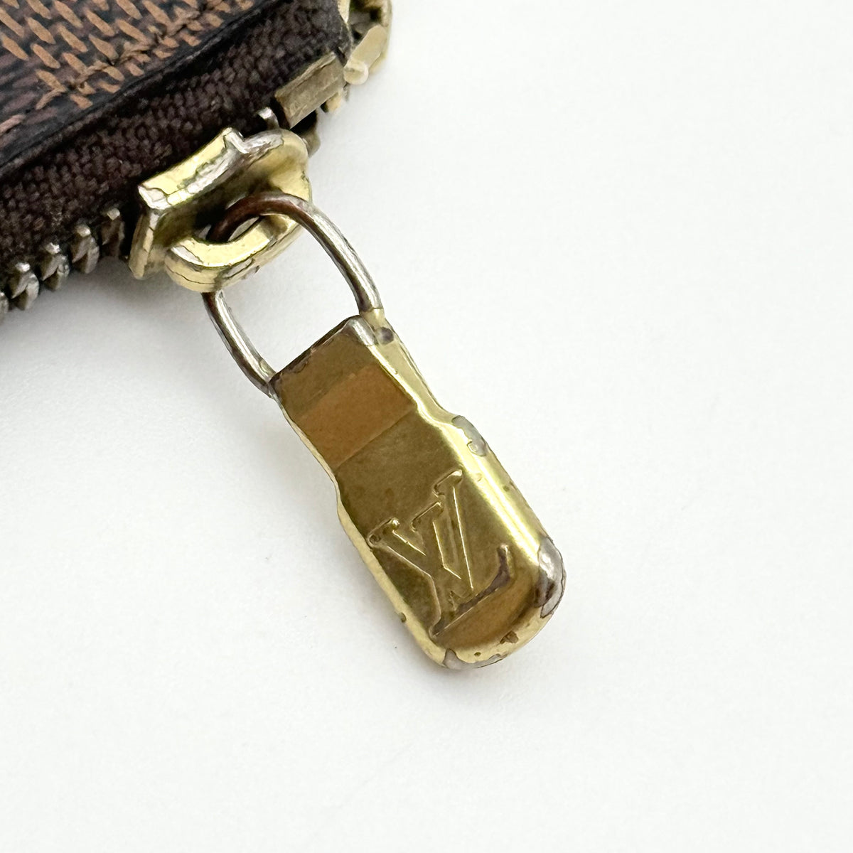 Louis Vuitton Damier Ebene key coin pouch in brown with gold-tone hardware and chain clasp, photographed on a white background.