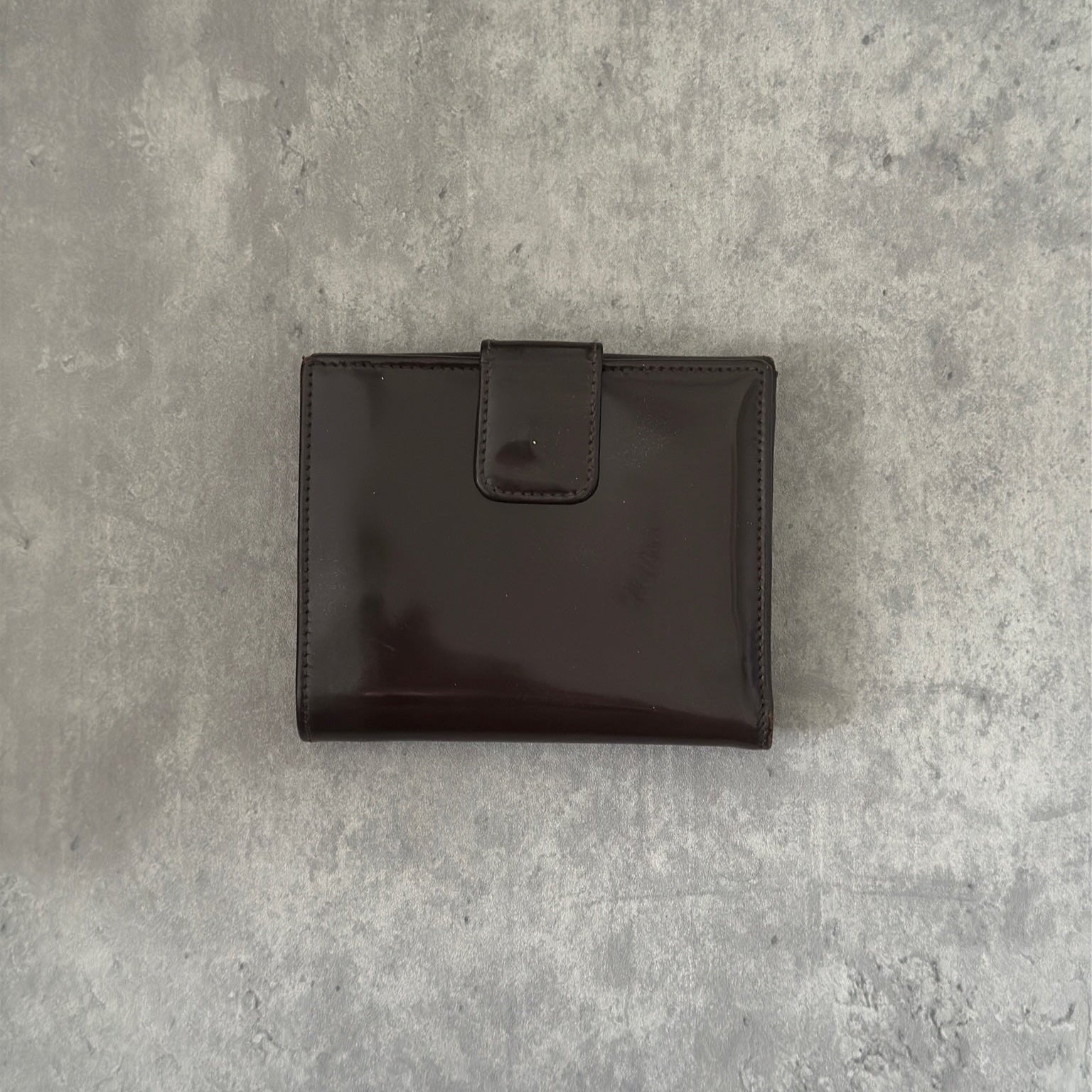 Gucci brown patent leather bifold wallet with multiple card slots and bill compartments, showcasing classic style and luxury.