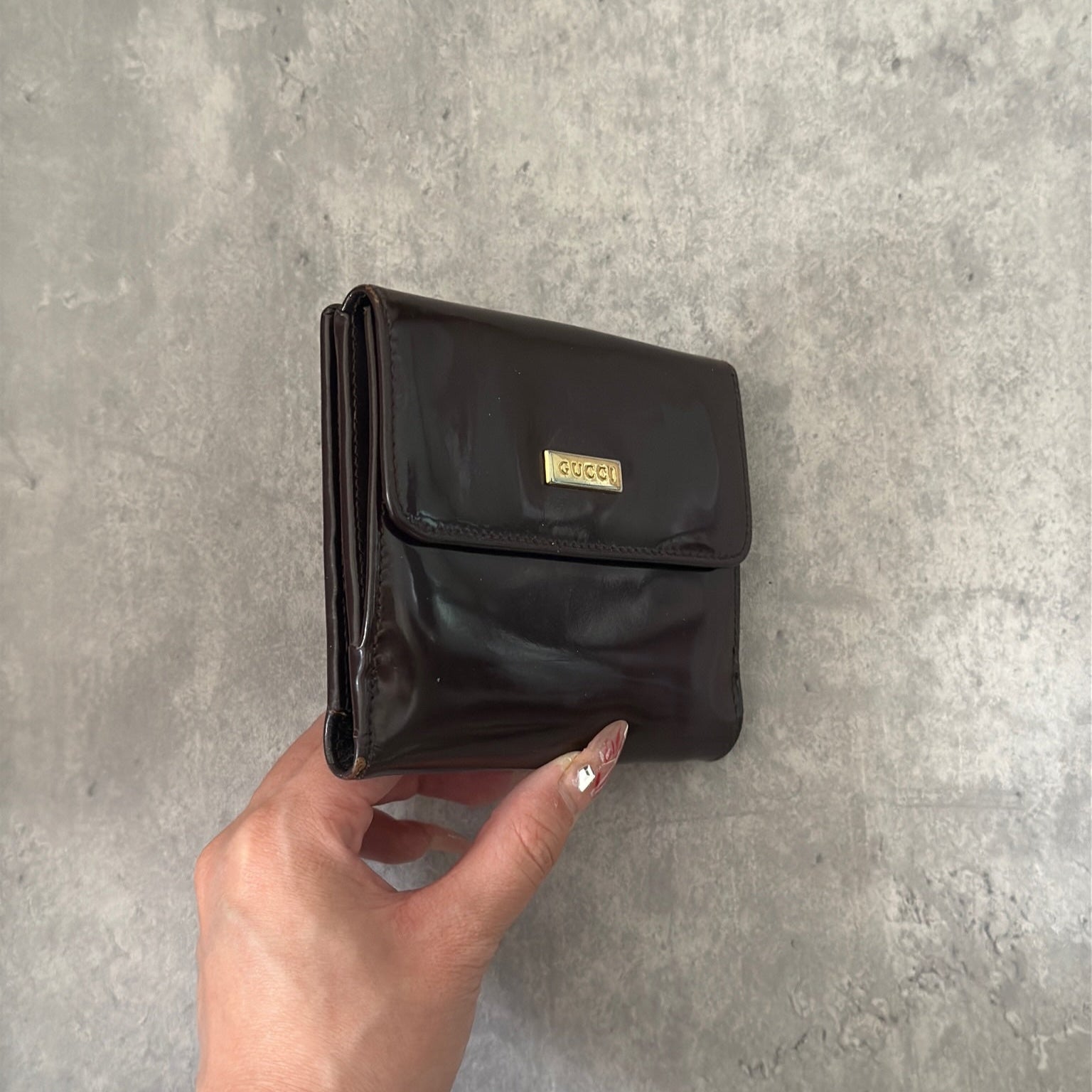 Gucci brown patent leather bifold wallet with multiple card slots and bill compartments, showcasing classic style and luxury.