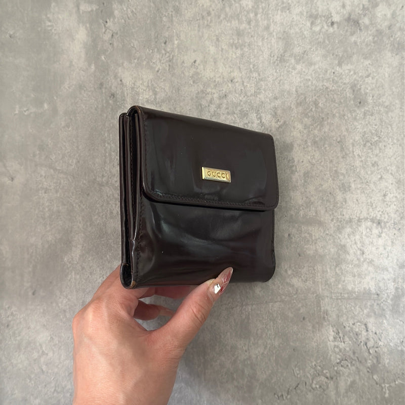 Gucci brown patent leather bifold wallet with multiple card slots and bill compartments, showcasing classic style and luxury.