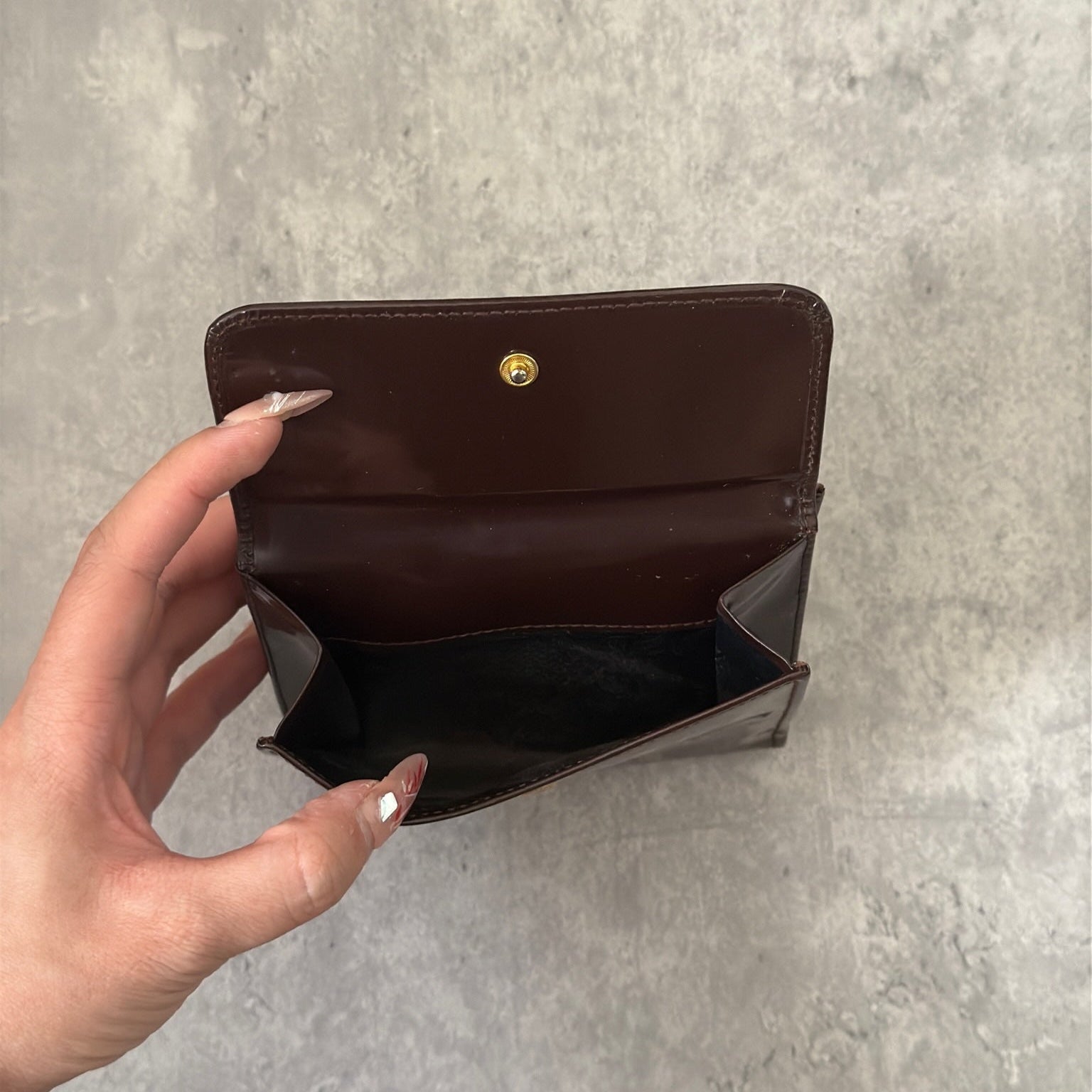Gucci brown patent leather bifold wallet with multiple card slots and bill compartments, showcasing classic style and luxury.