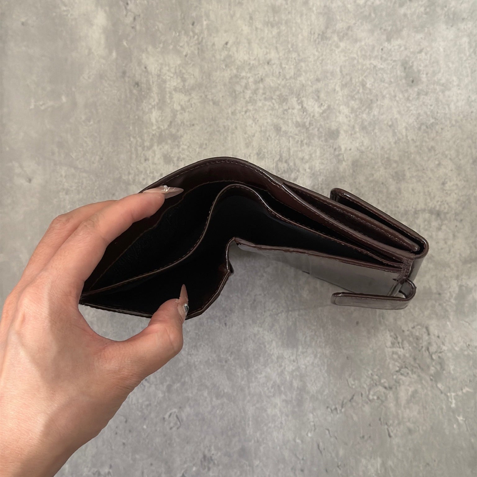 Gucci brown patent leather bifold wallet with multiple card slots and bill compartments, showcasing classic style and luxury.