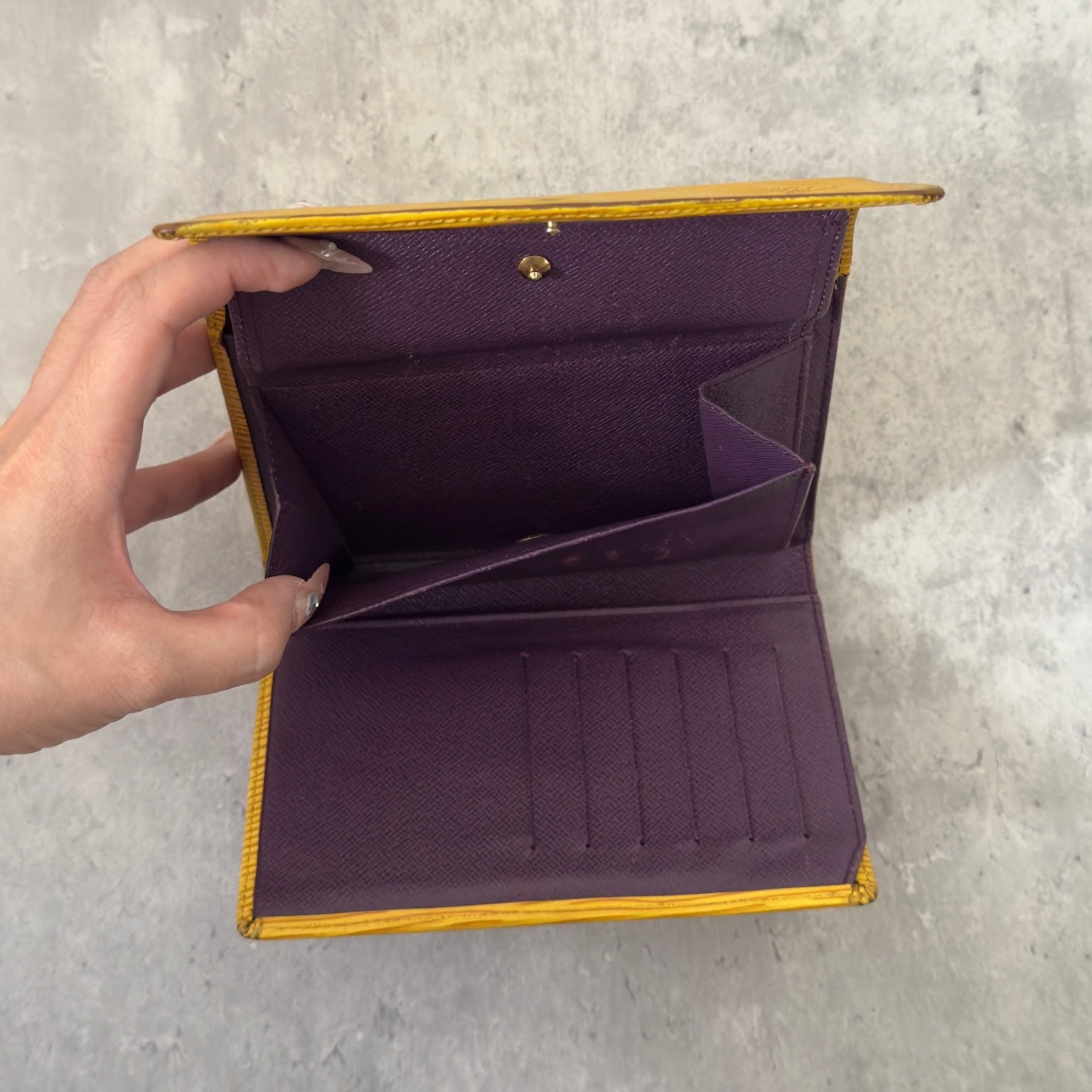 Louis Vuitton Epi leather wallet in yellow with purple leather interior, showcasing multiple card slots and a spacious bill compartment, a blend of functionality and luxury.