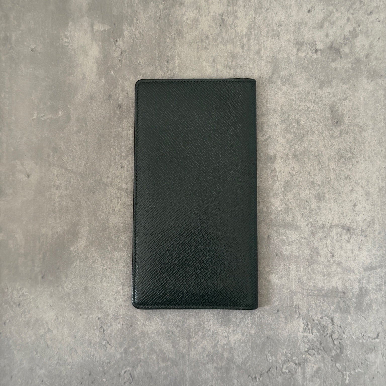 Louis Vuitton Taiga Porte-Valeurs long wallet in green, showcasing the embossed LV logo and a structured interior with multiple card slots and compartments, embodying luxury and organization.