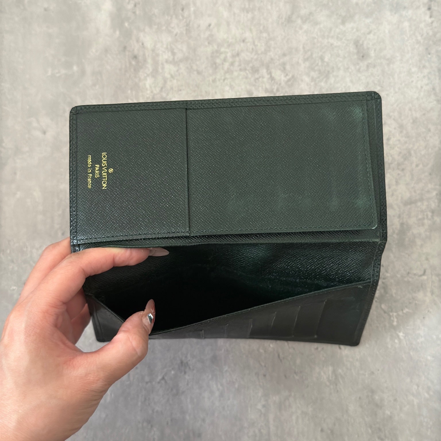 Louis Vuitton Taiga Porte-Valeurs long wallet in green, showcasing the embossed LV logo and a structured interior with multiple card slots and compartments, embodying luxury and organization.