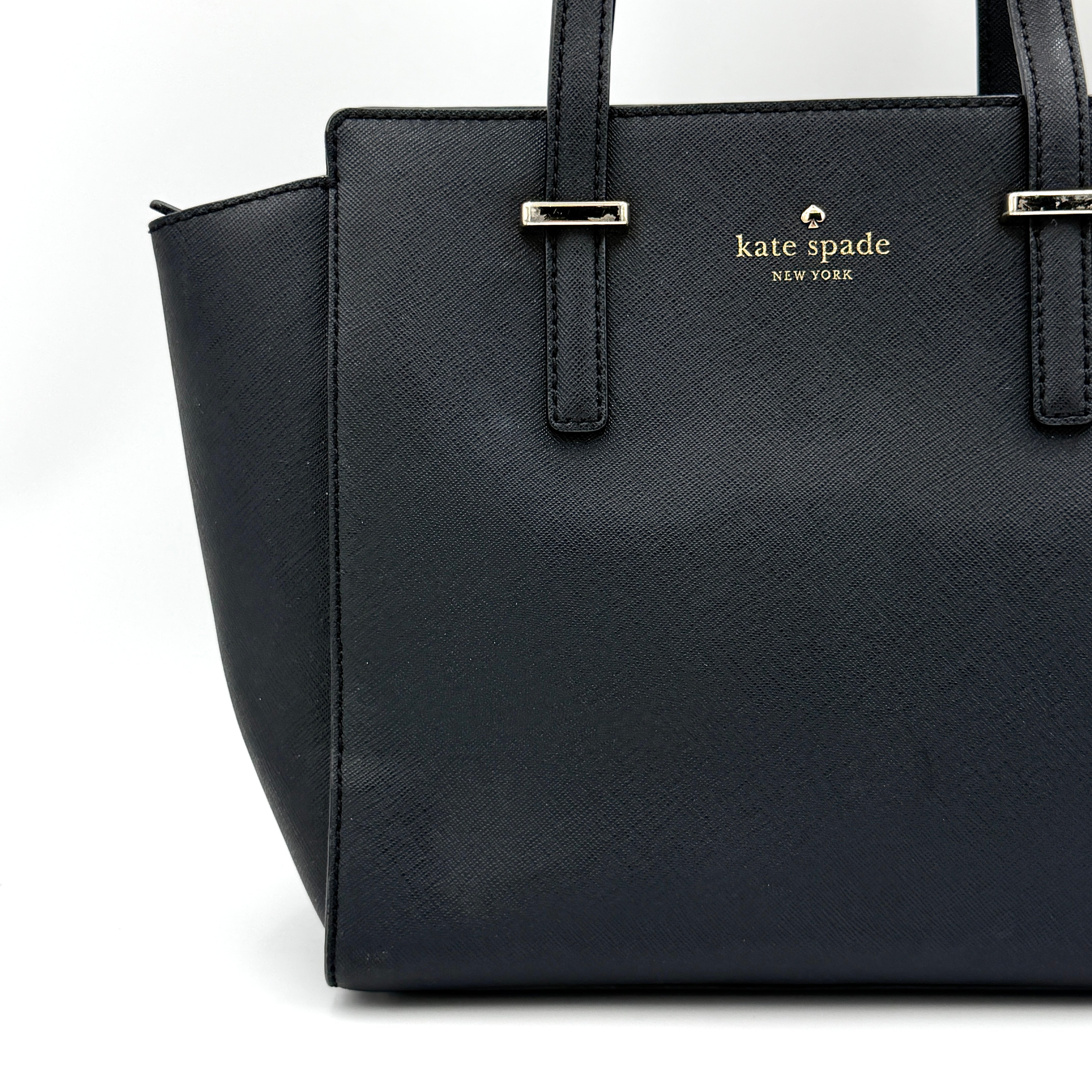 Kate Spade black Hayden handbag with structured handles and a detachable strap displayed beside it.