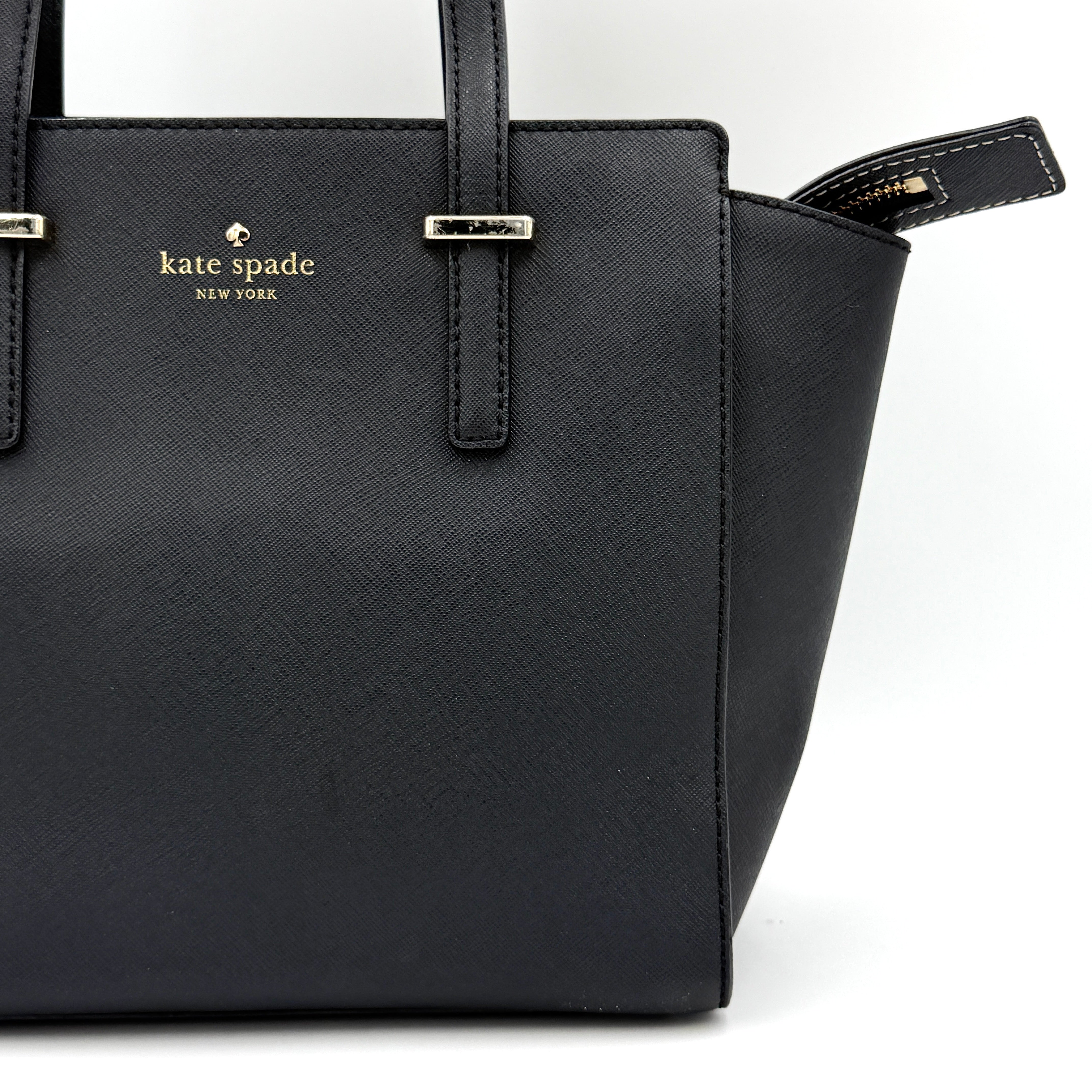 Kate Spade black Hayden handbag with structured handles and a detachable strap displayed beside it.