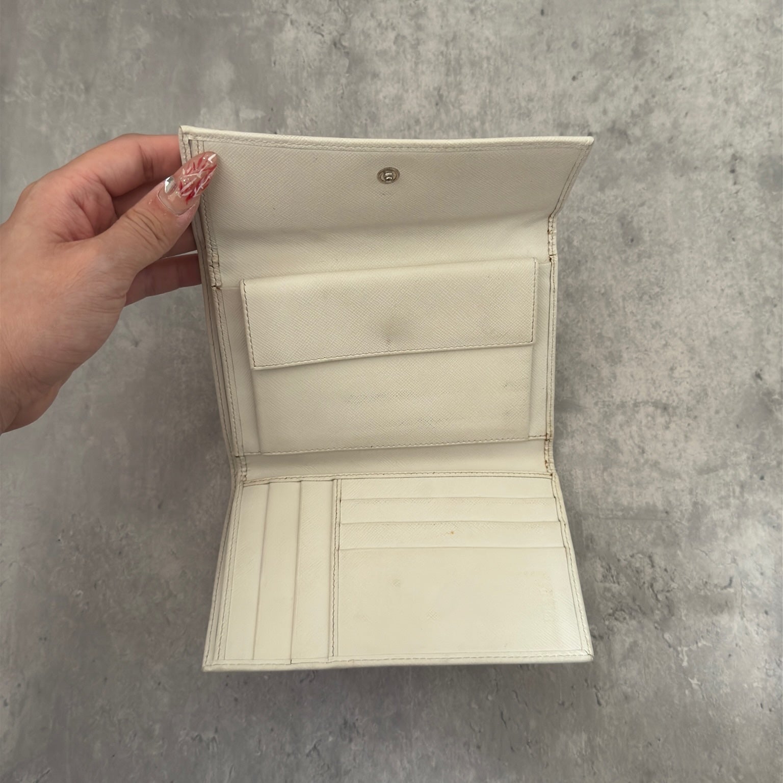 Pre-loved Prada Tessuto Nero leather trifold wallet with triangle logo plate in off-white, featuring card slots and a snap closure.