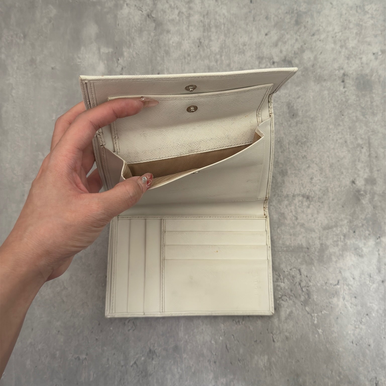 Pre-loved Prada Tessuto Nero leather trifold wallet with triangle logo plate in off-white, featuring card slots and a snap closure.