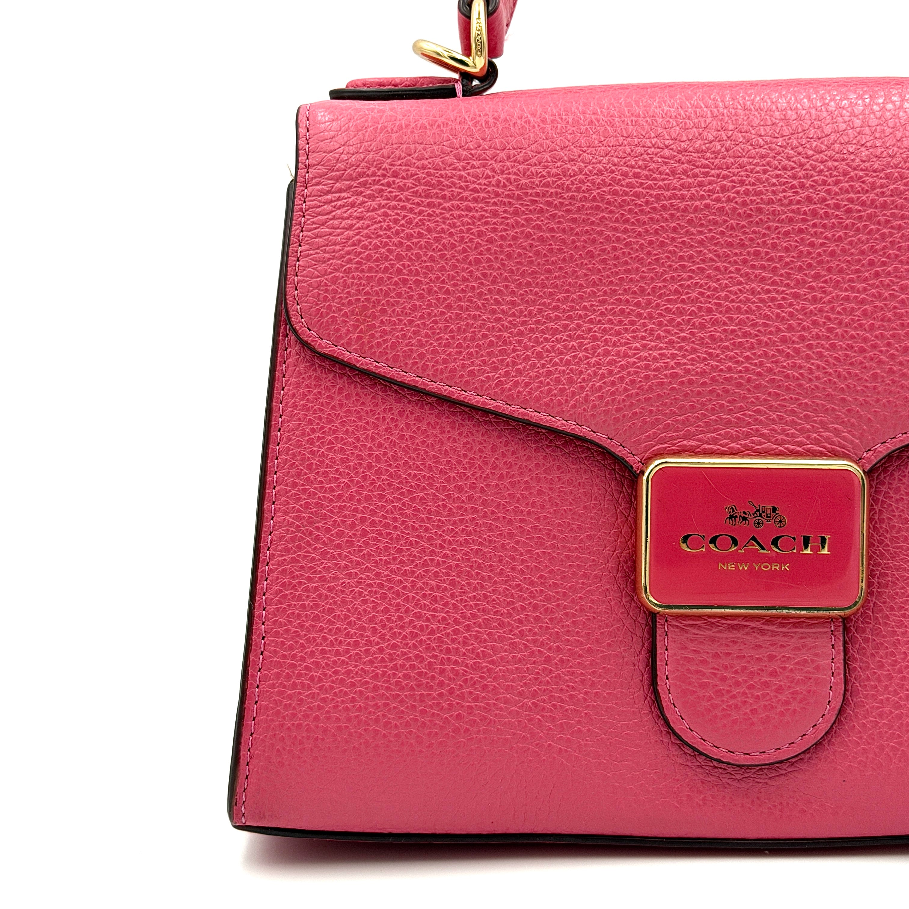 Coach Pepper Satchel in bold pink pebbled leather, featuring a structured silhouette and gold logo push-lock hardware.