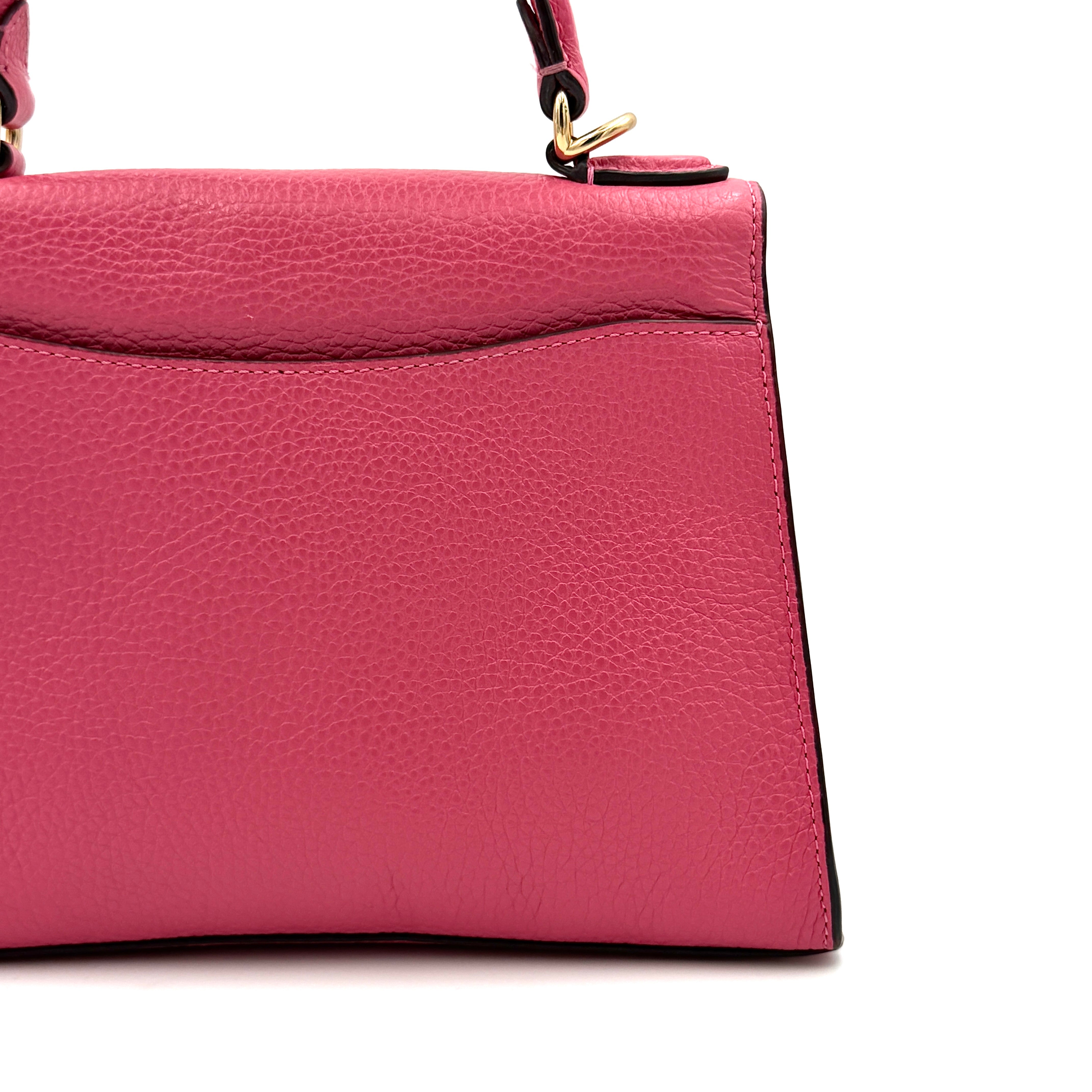 Coach Pepper Satchel in bold pink pebbled leather, featuring a structured silhouette and gold logo push-lock hardware.
