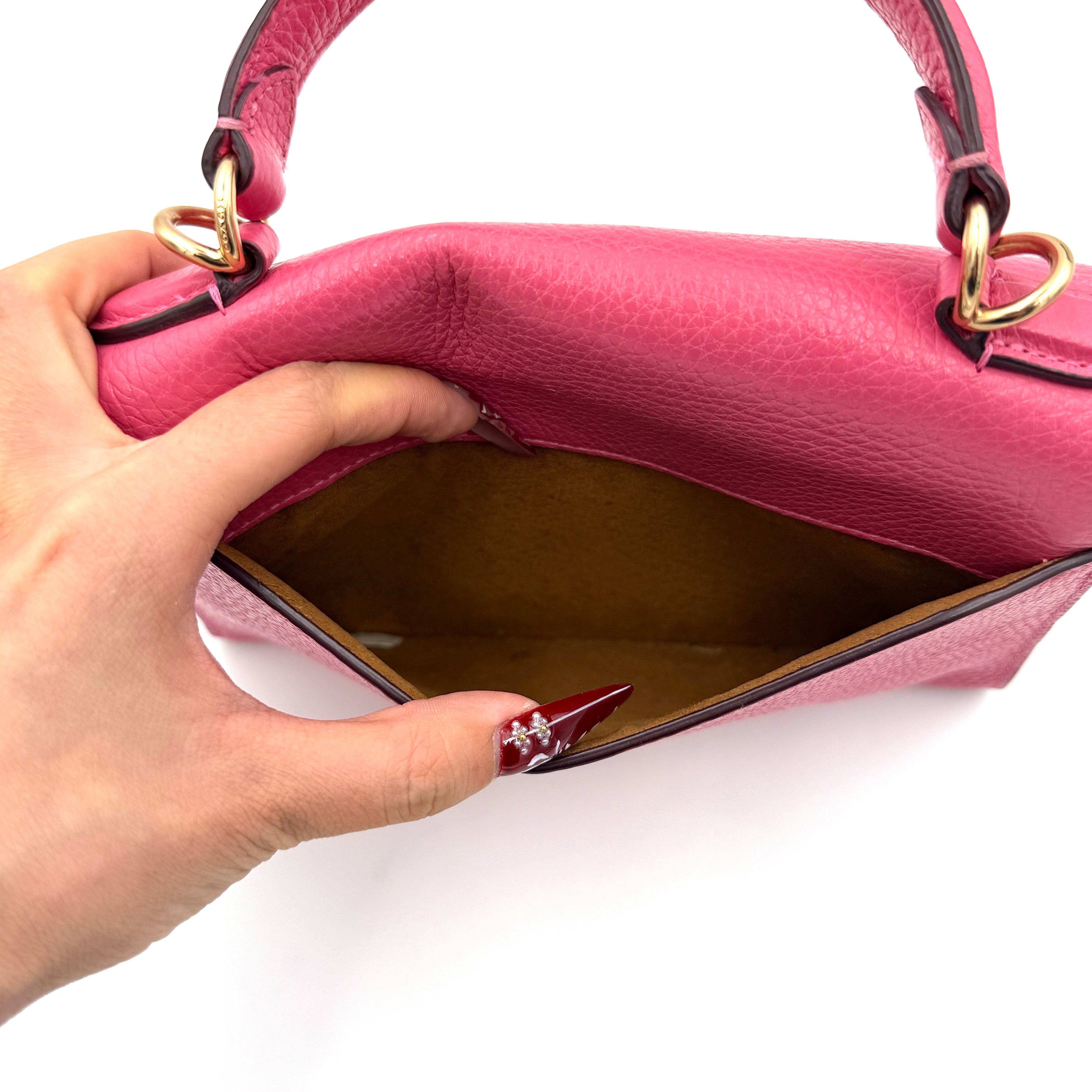 Coach Pepper Satchel in bold pink pebbled leather, featuring a structured silhouette and gold logo push-lock hardware.