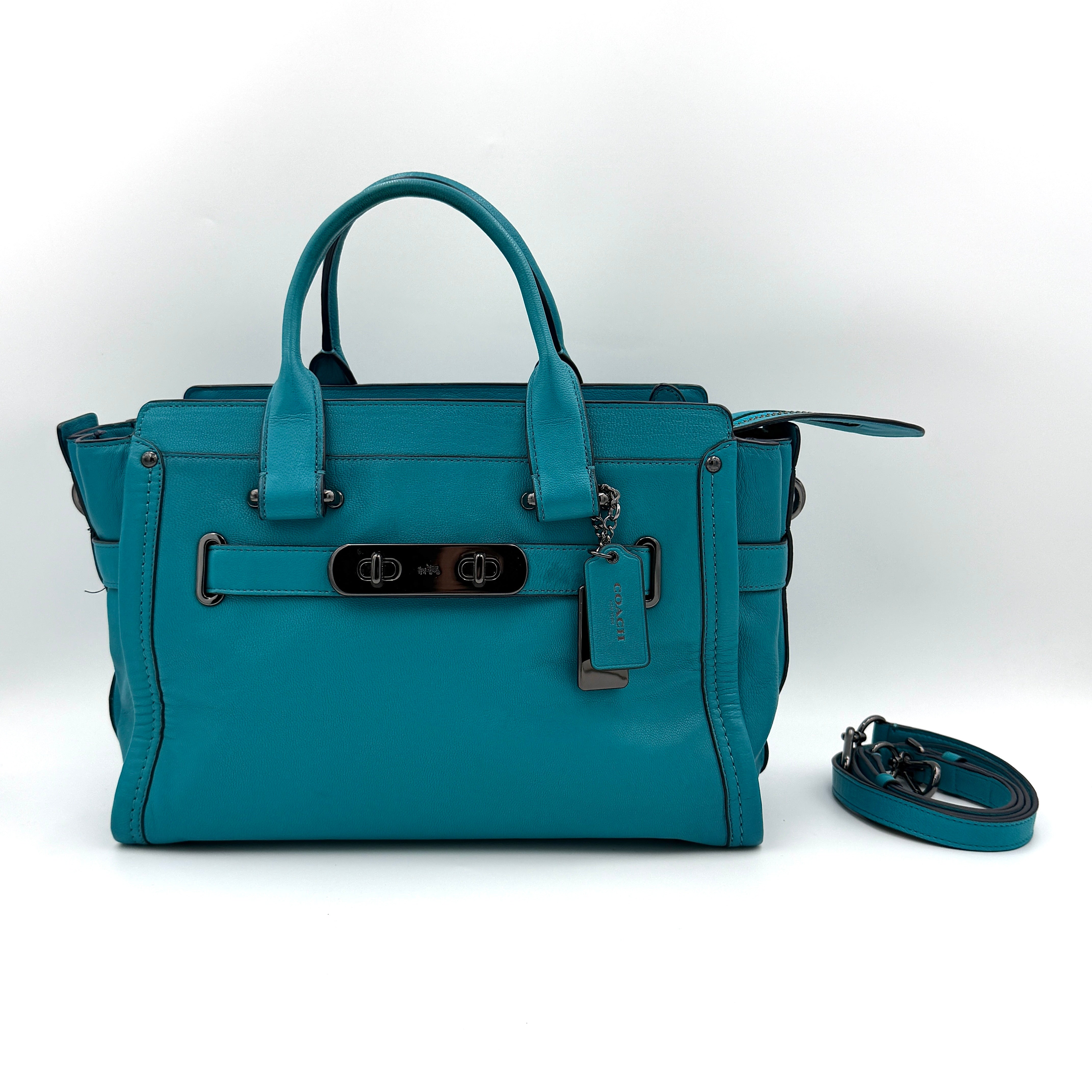 Coach Swagger 27 Carryall in vivid turquoise leather with double top handles, gunmetal hardware, and detachable strap.