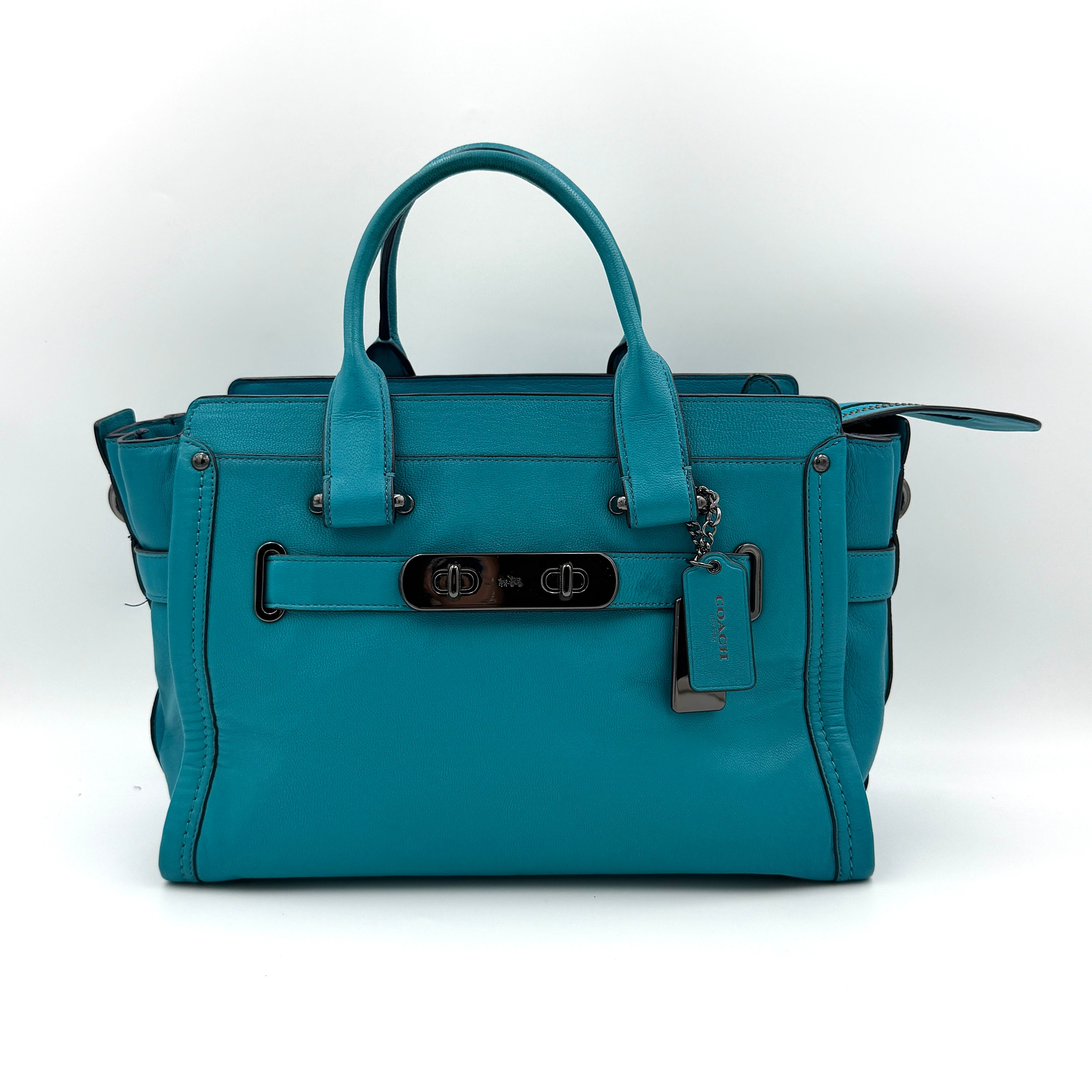 Coach Swagger 27 Carryall in vivid turquoise leather with double top handles, gunmetal hardware, and detachable strap.