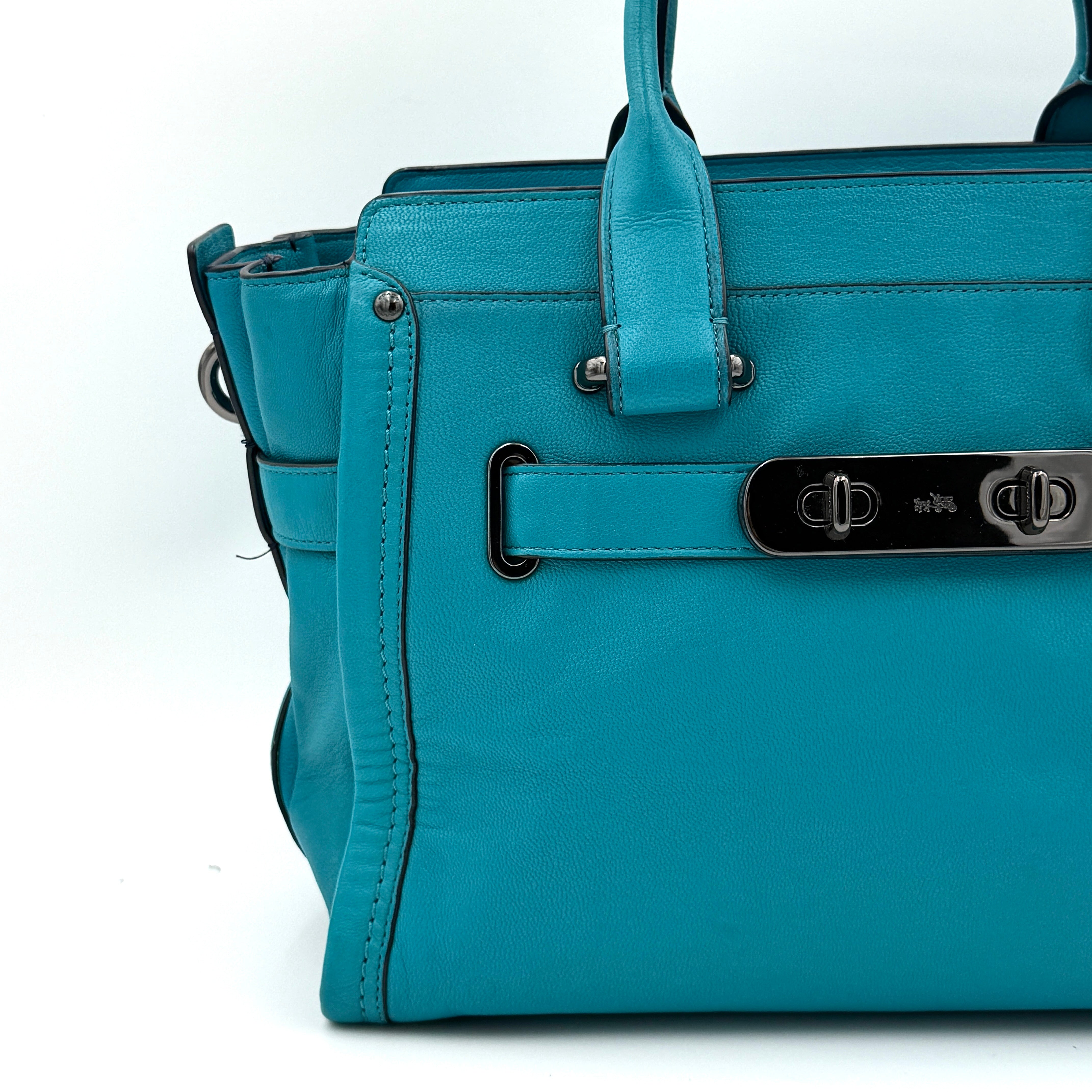 Coach Swagger 27 Carryall in vivid turquoise leather with double top handles, gunmetal hardware, and detachable strap.