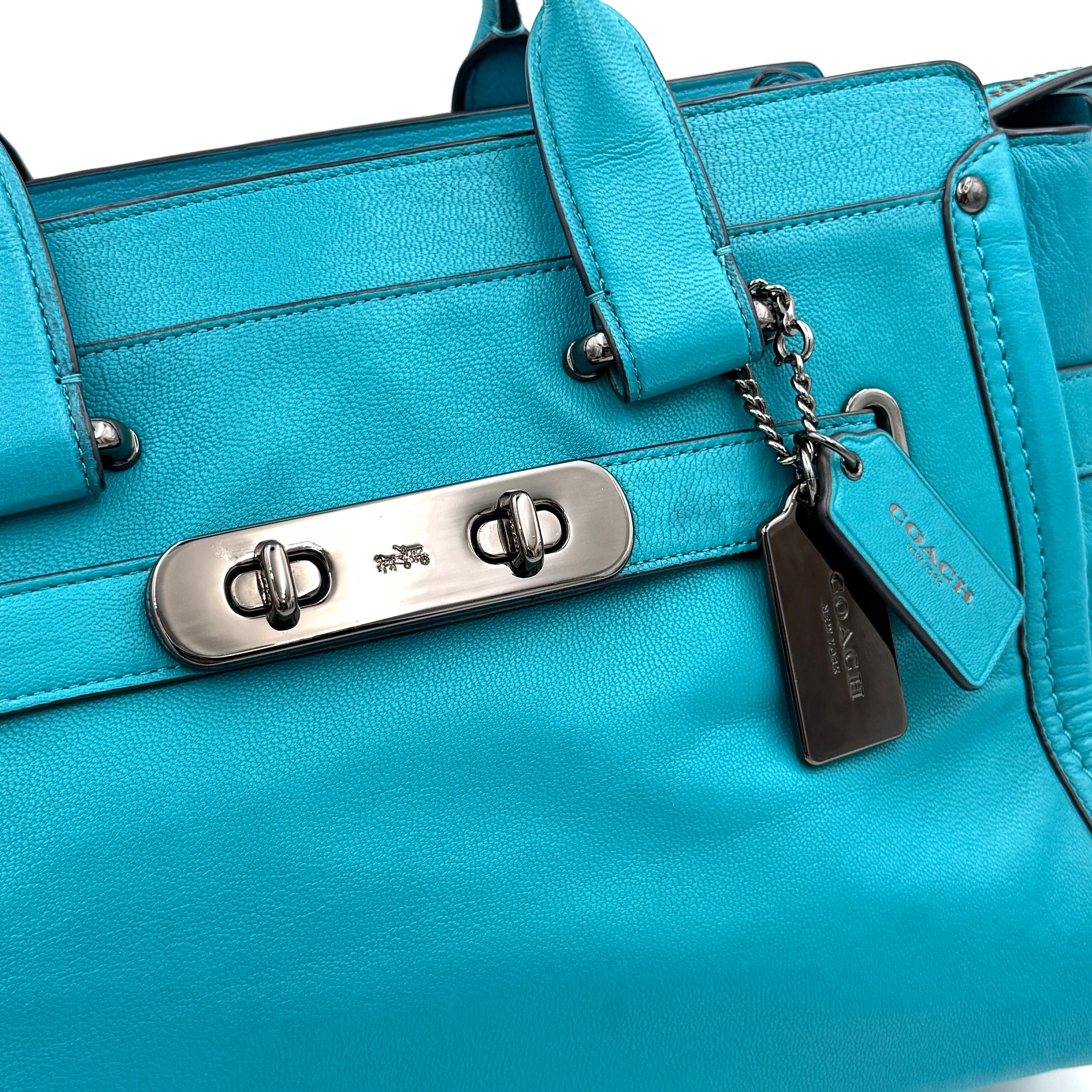 Coach Swagger 27 Carryall in vivid turquoise leather with double top handles, gunmetal hardware, and detachable strap.