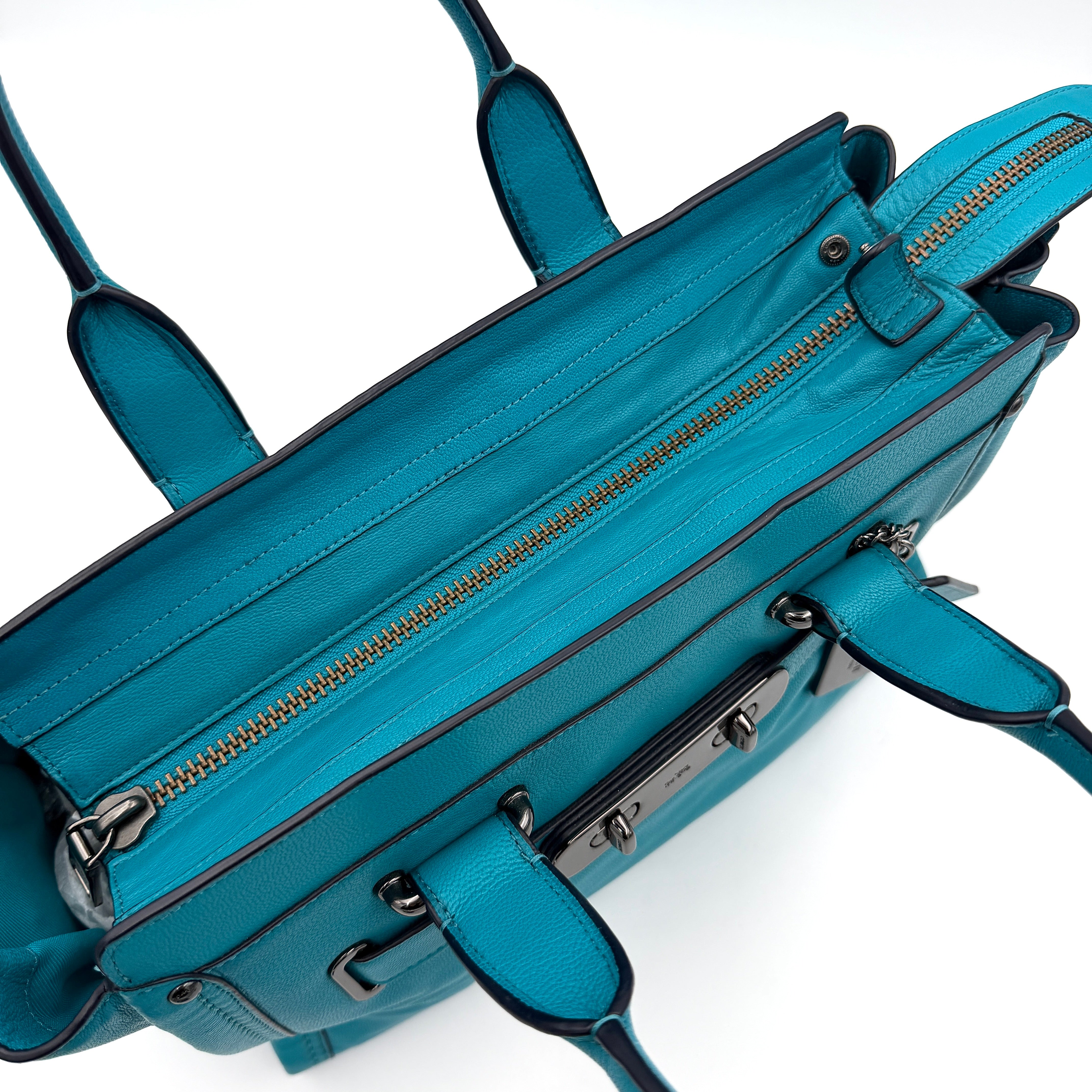 Coach Swagger 27 Carryall in vivid turquoise leather with double top handles, gunmetal hardware, and detachable strap.