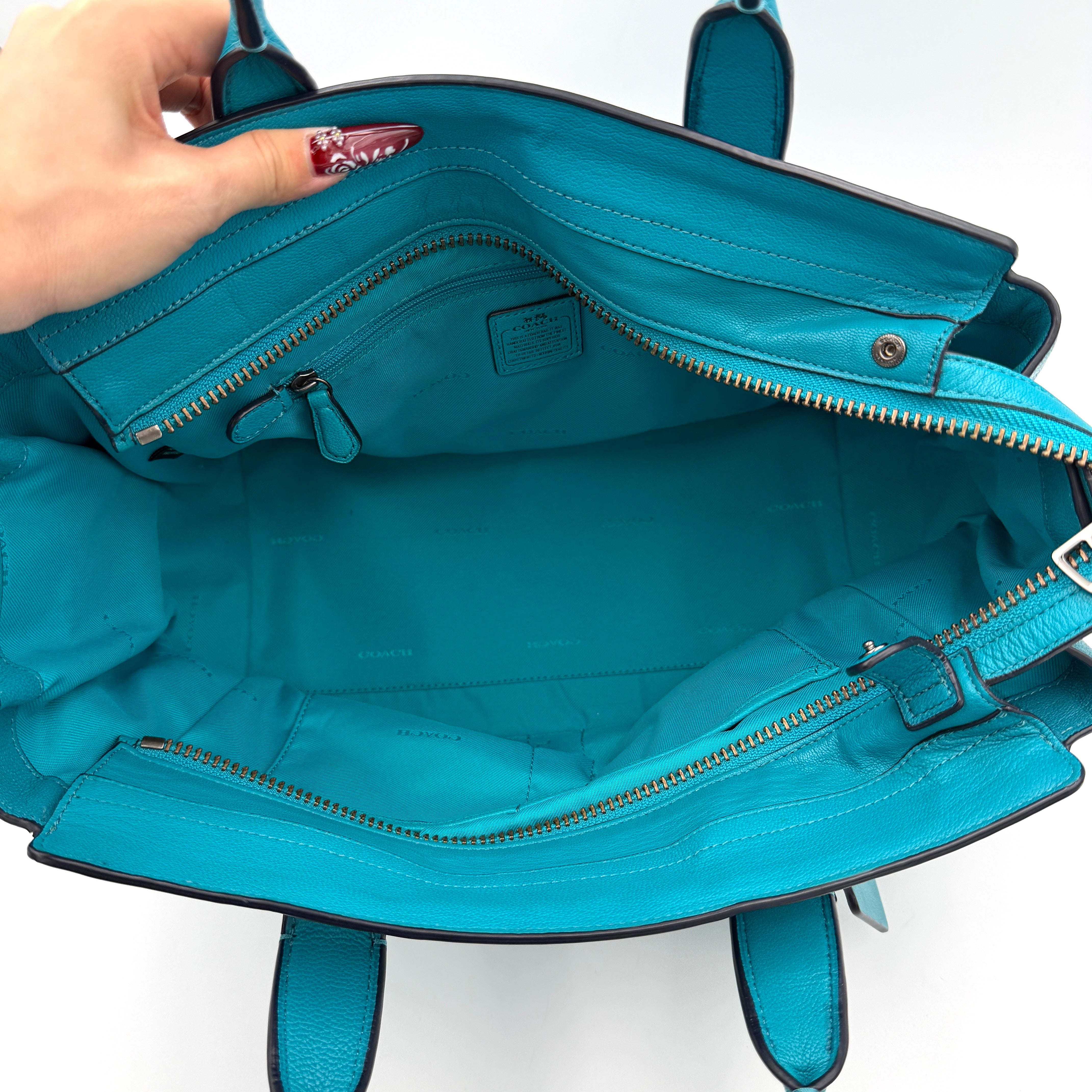 Coach Swagger 27 Carryall in vivid turquoise leather with double top handles, gunmetal hardware, and detachable strap.