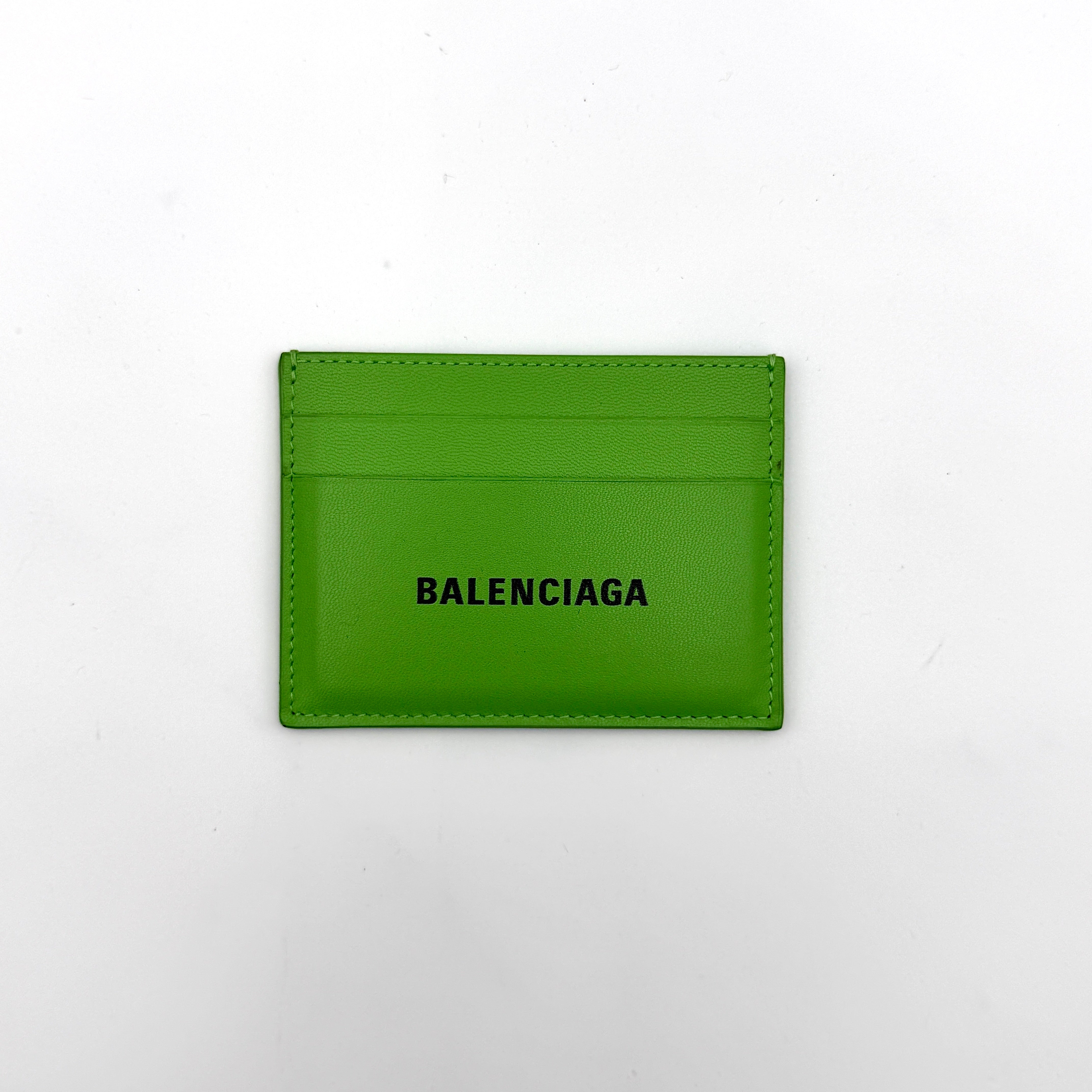A vivid green Balenciaga leather cardholder featuring a bold black logo and minimalist silhouette.