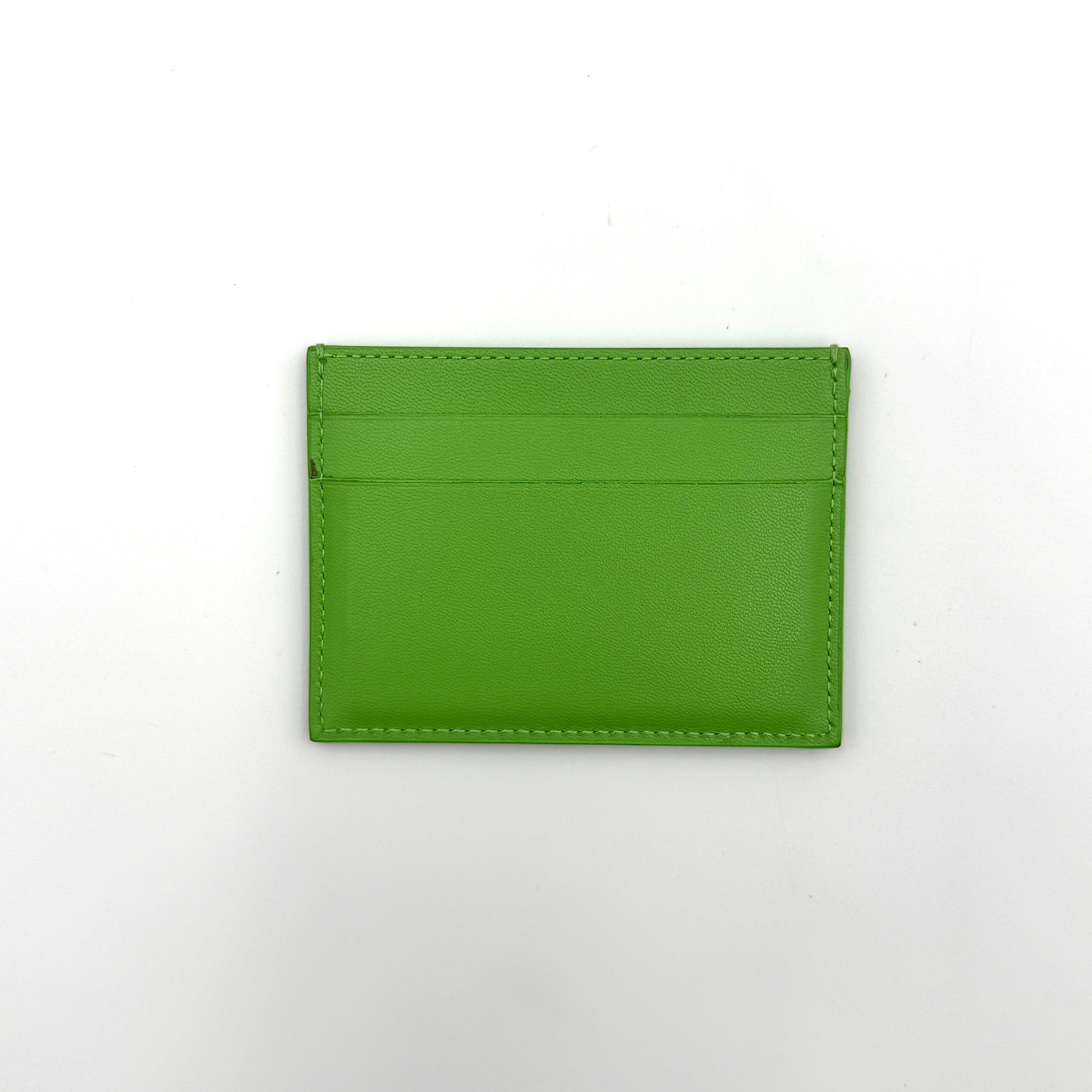 A vivid green Balenciaga leather cardholder featuring a bold black logo and minimalist silhouette.