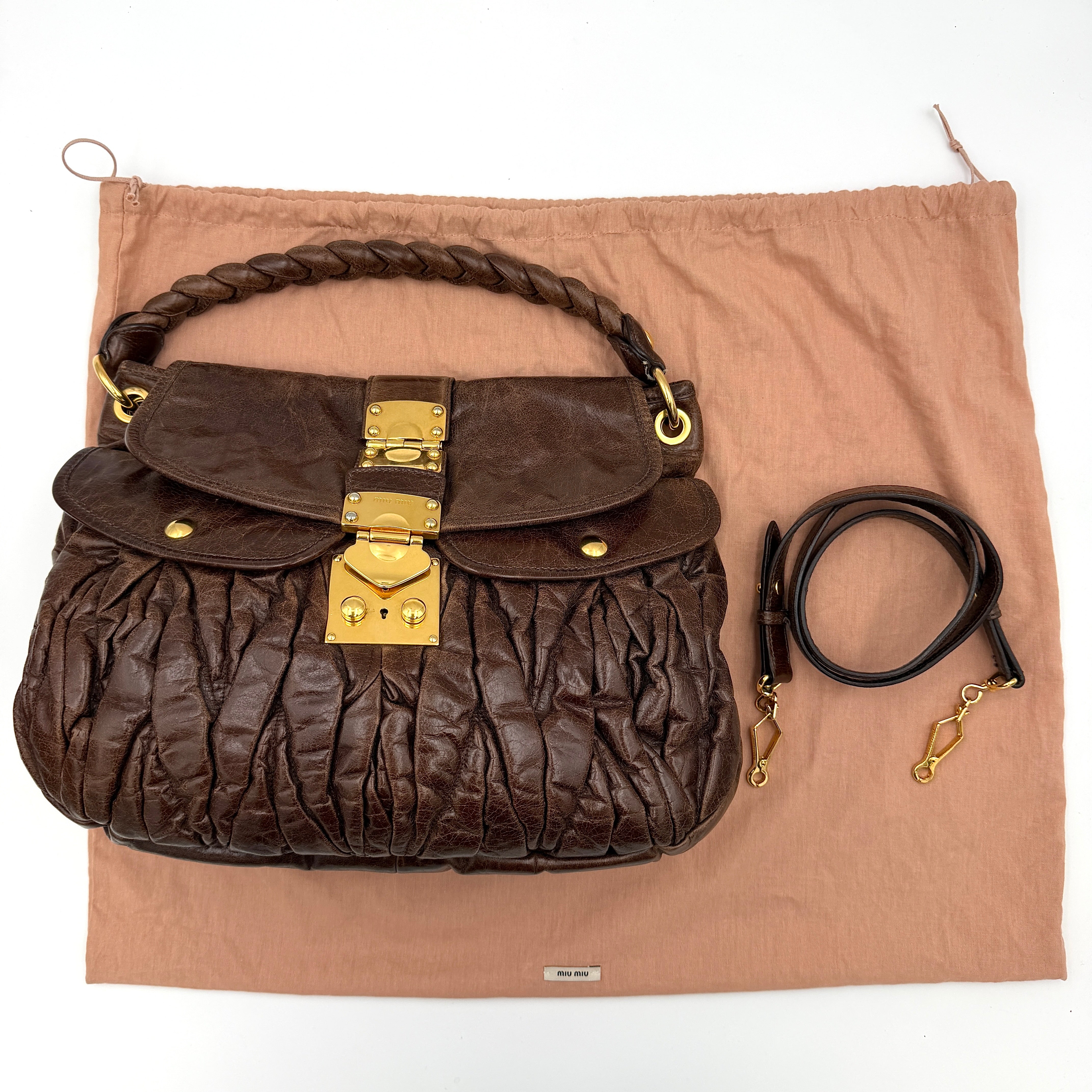 Miu Miu Coffer Hobo bag in deep brown matelassé leather with braided handle, gold hardware, and detachable strap.