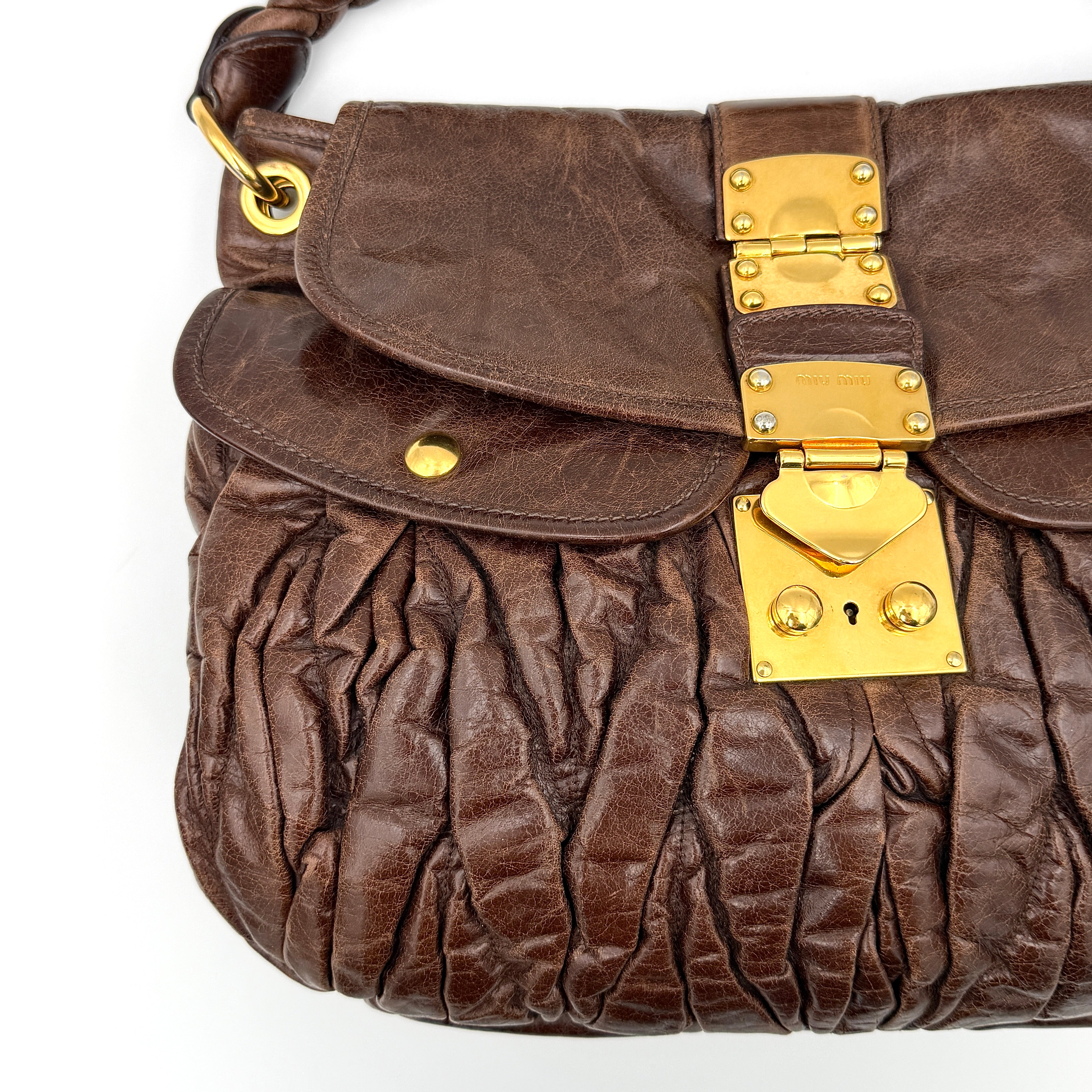 Miu Miu Coffer Hobo bag in deep brown matelassé leather with braided handle, gold hardware, and detachable strap.