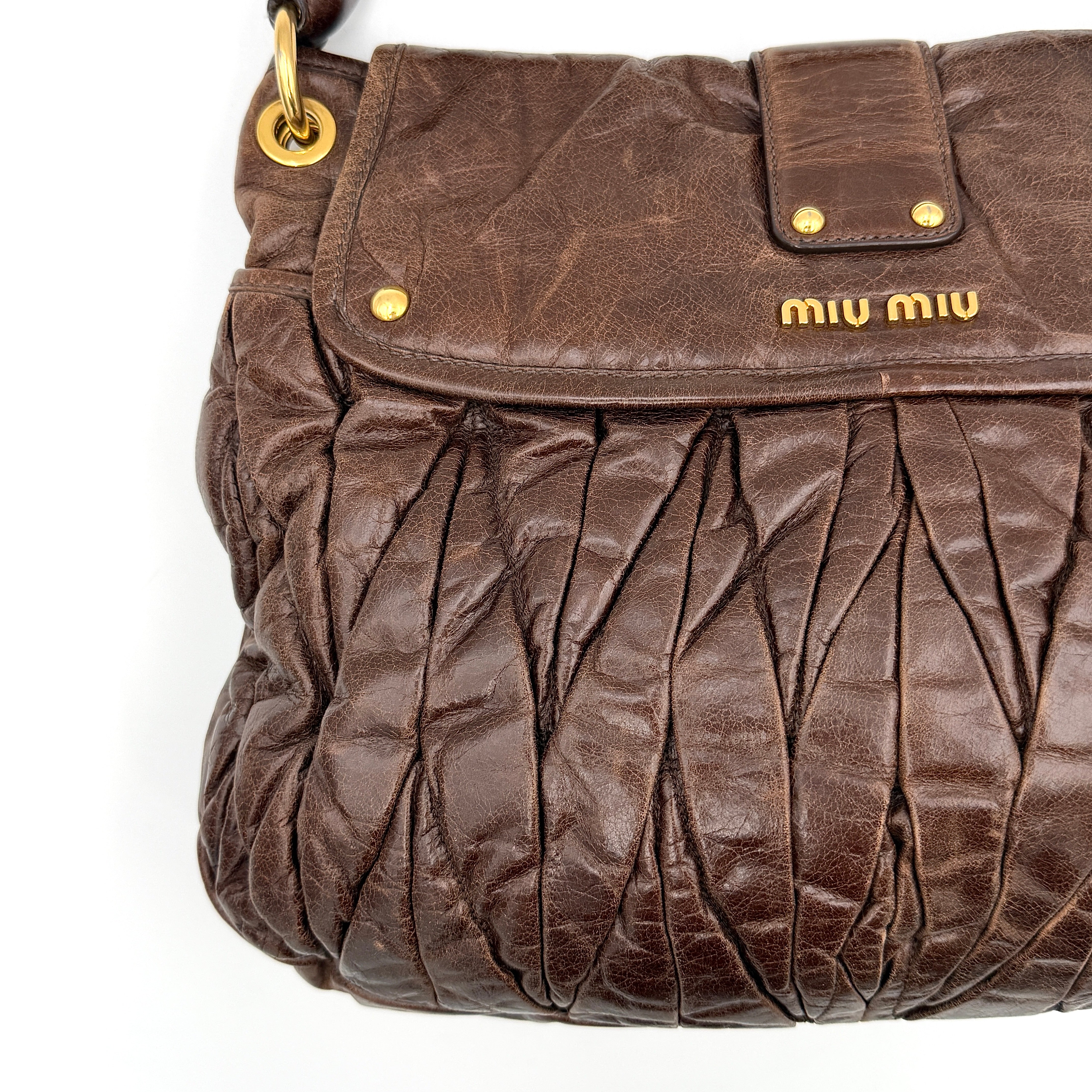 Miu Miu Coffer Hobo bag in deep brown matelassé leather with braided handle, gold hardware, and detachable strap.
