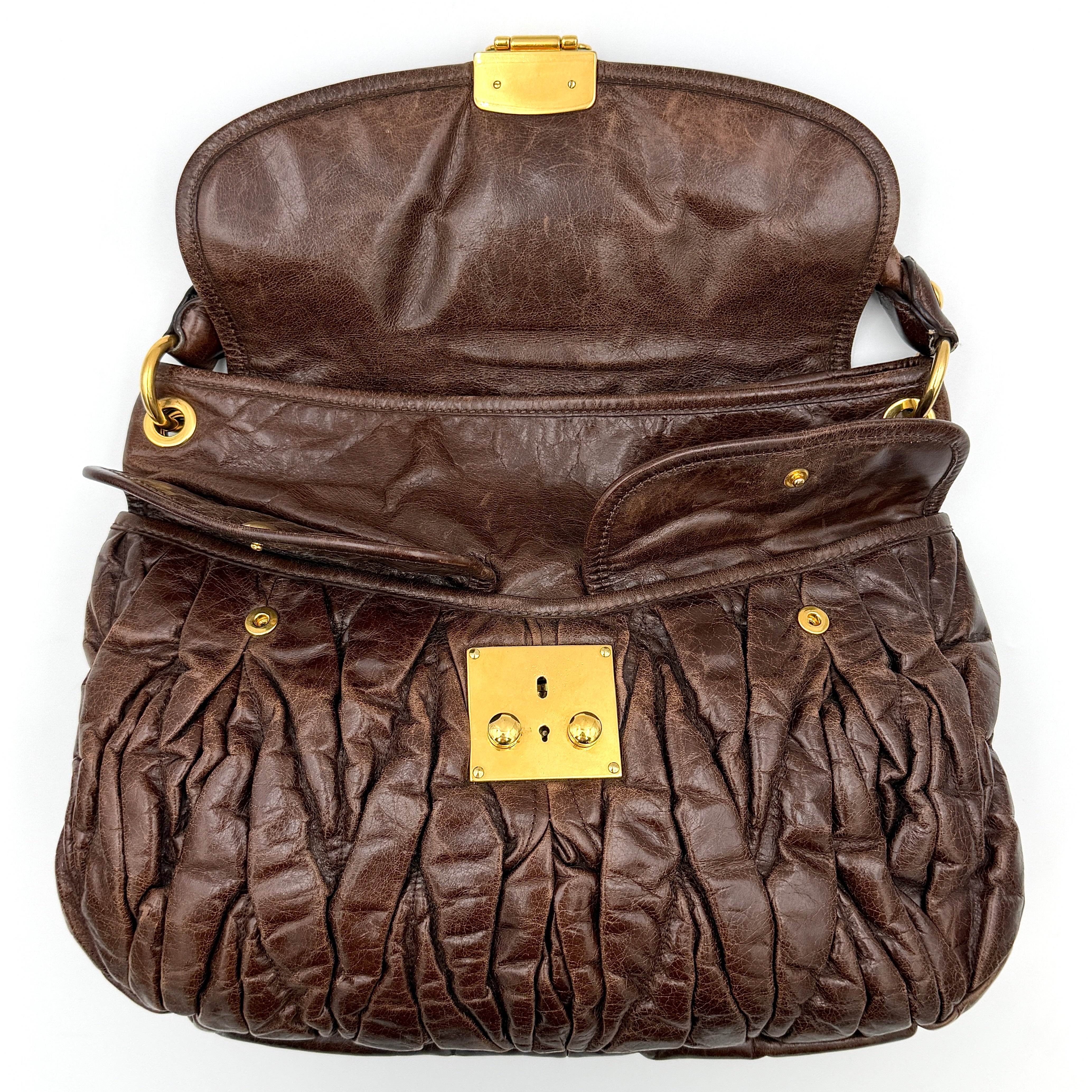 Miu Miu Coffer Hobo bag in deep brown matelassé leather with braided handle, gold hardware, and detachable strap.