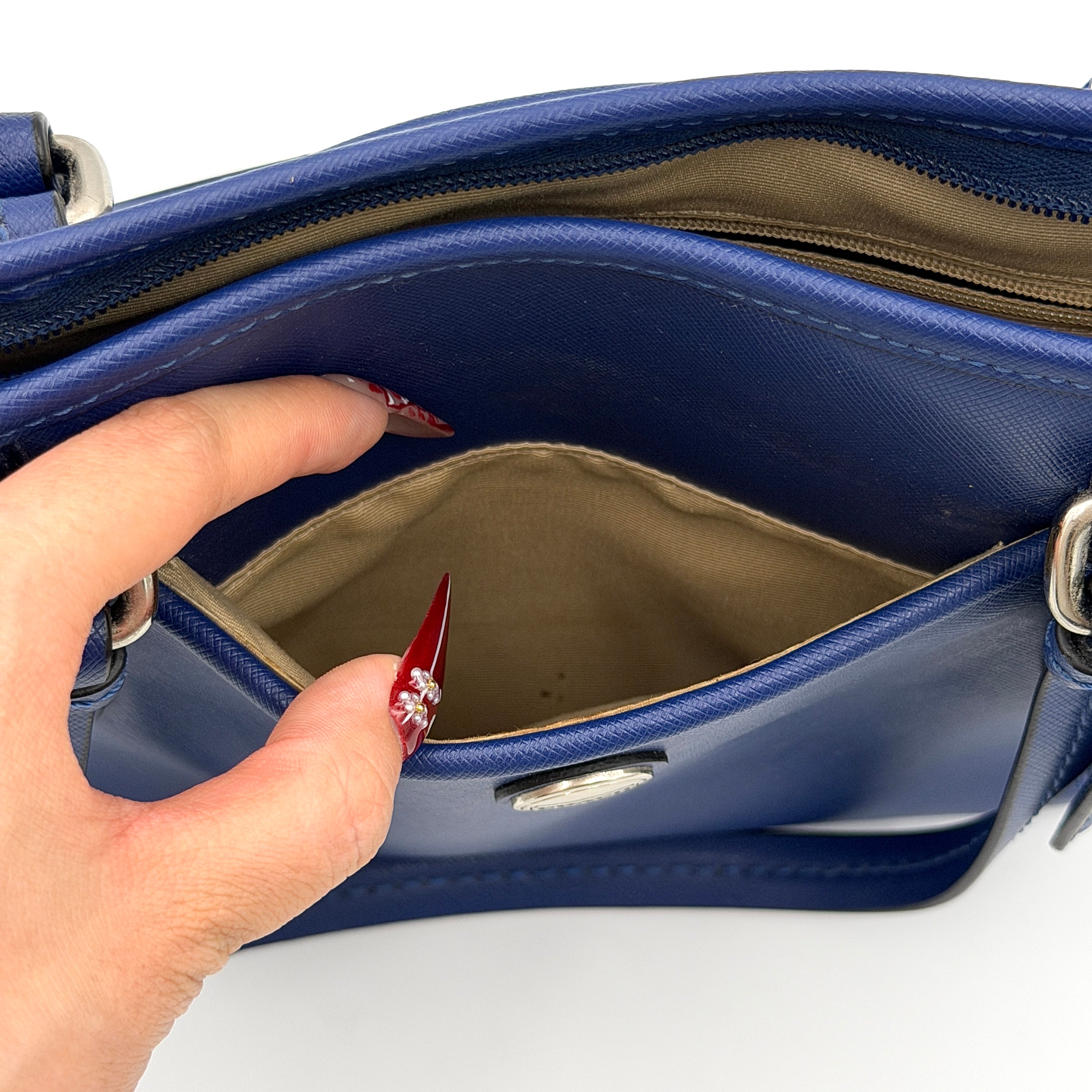 A structured cobalt blue Coach tote bag with silver hardware, dual handles, and an optional crossbody strap, displayed against a clean background.