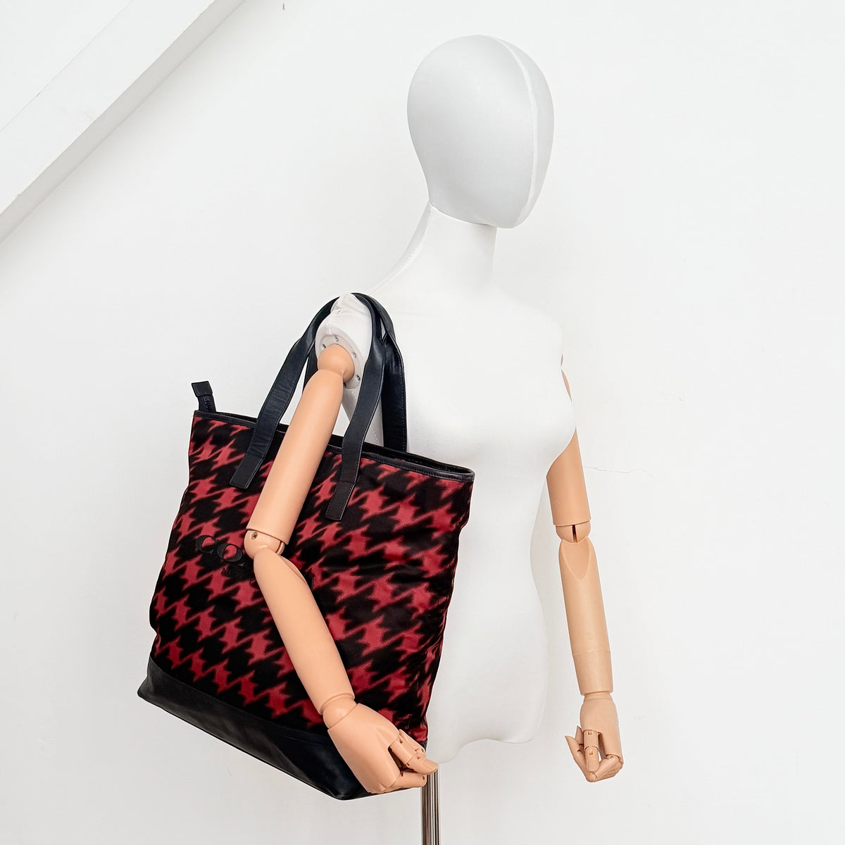 Coach Mercer Print Houndstooth Tote Bag in red and black with leather trim and handles, photographed upright against a white background.