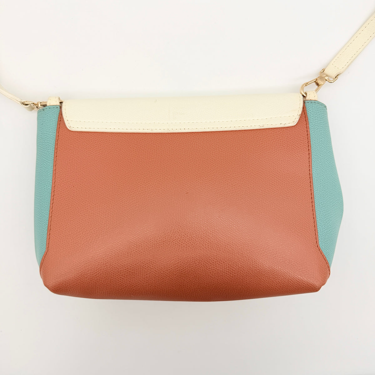 Furla Kelis crossbody bag in brown, blue, and cream leather with envelope flap and gold-tone hardware, displayed on a Furla dust bag.
