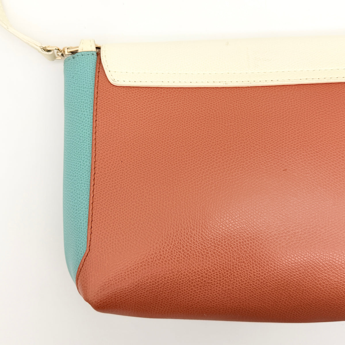 Furla Kelis crossbody bag in brown, blue, and cream leather with envelope flap and gold-tone hardware, displayed on a Furla dust bag.