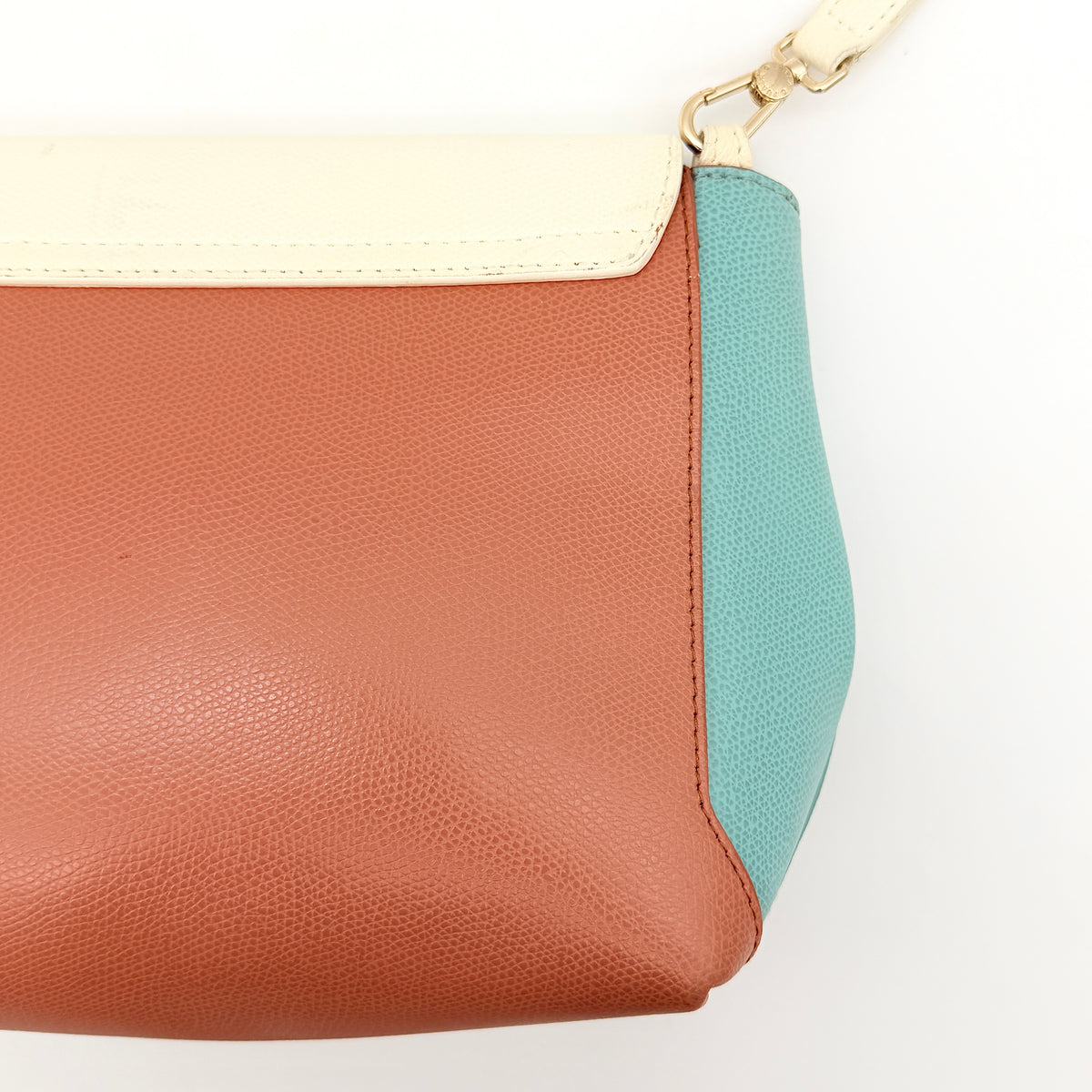 Furla Kelis crossbody bag in brown, blue, and cream leather with envelope flap and gold-tone hardware, displayed on a Furla dust bag.
