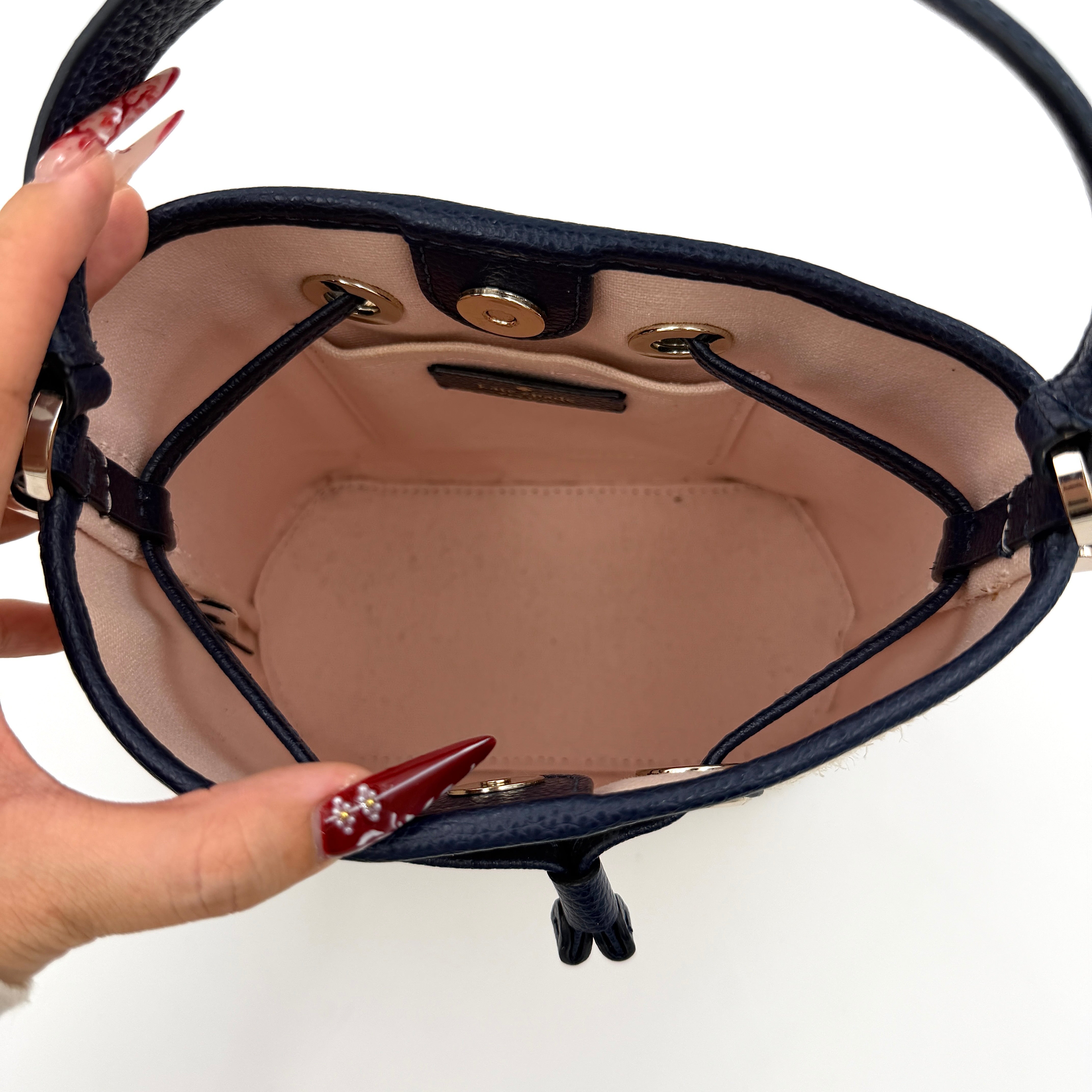 Front view of the Kate Spade Eva Straw Bucket Bag in cream, with navy leather trim and silver-tone hardware.