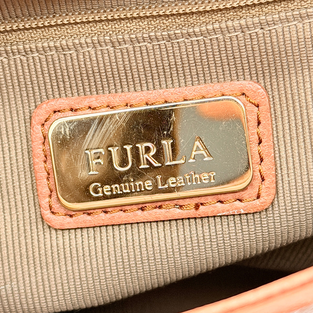 Furla Kelis crossbody bag in brown, blue, and cream leather with envelope flap and gold-tone hardware, displayed on a Furla dust bag.