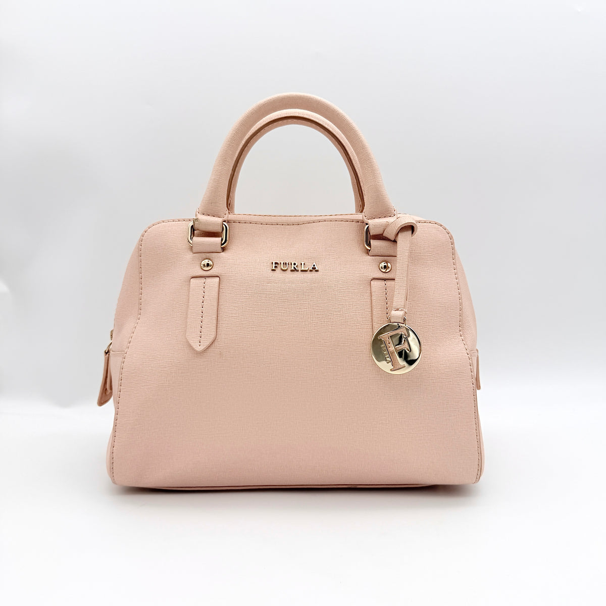 Furla Elena 2Way Saffiano leather satchel in beige with gold-tone hardware and removable strap, displayed on Furla-branded dust bag.