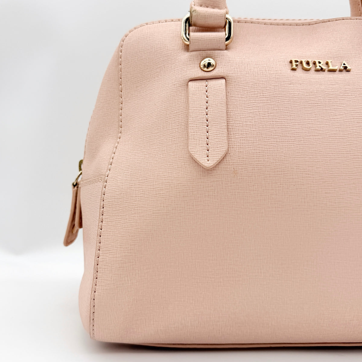 Furla Elena 2Way Saffiano leather satchel in beige with gold-tone hardware and removable strap, displayed on Furla-branded dust bag.