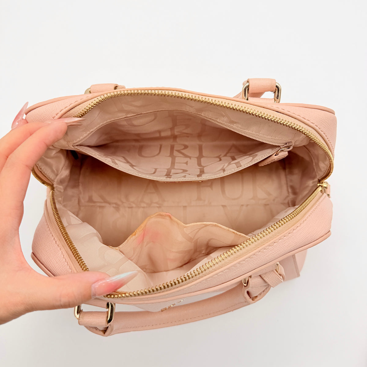 Furla Elena 2Way Saffiano leather satchel in beige with gold-tone hardware and removable strap, displayed on Furla-branded dust bag.