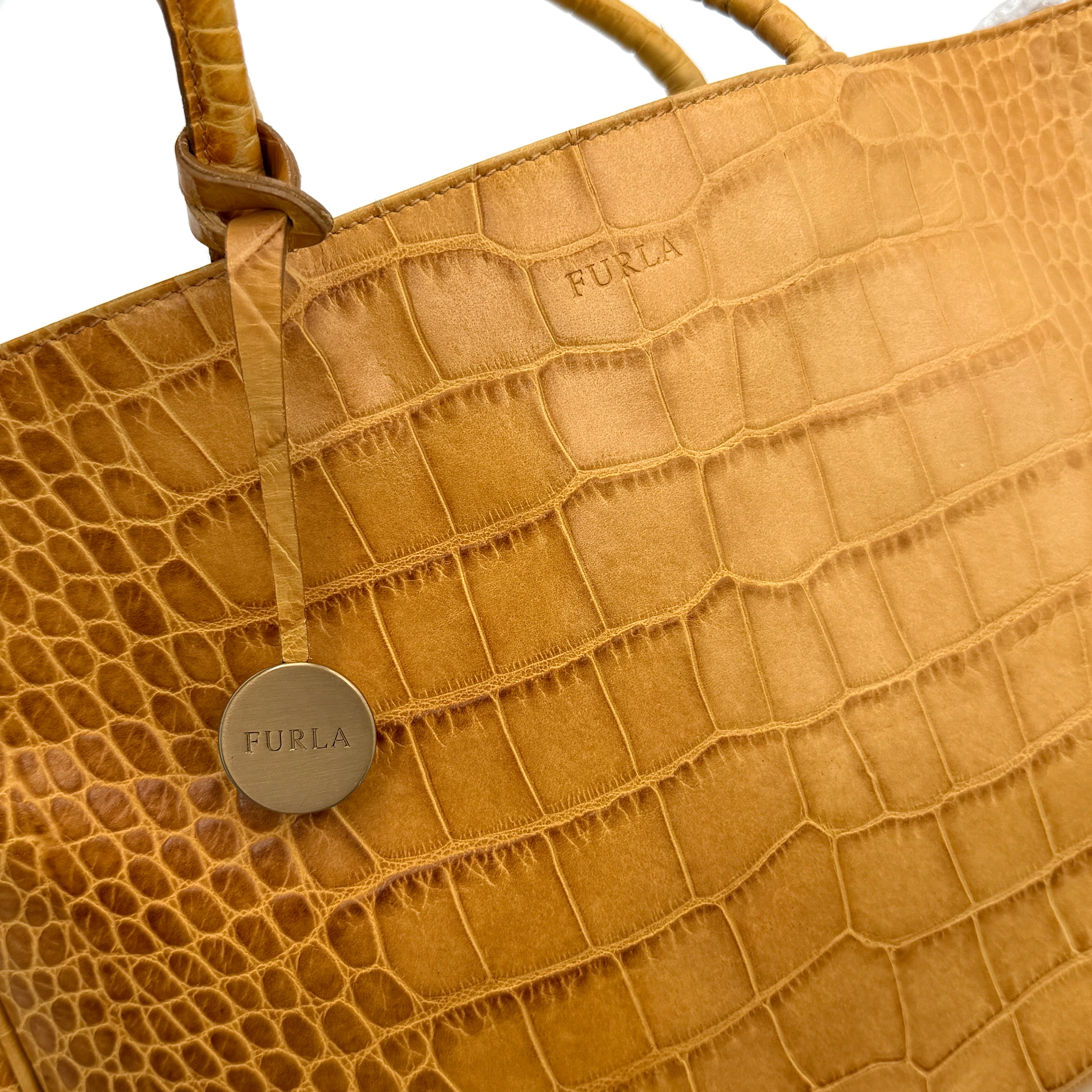 Furla yellow croc-embossed leather tote bag with double handles and matte gold logo charm, presented against a white background.