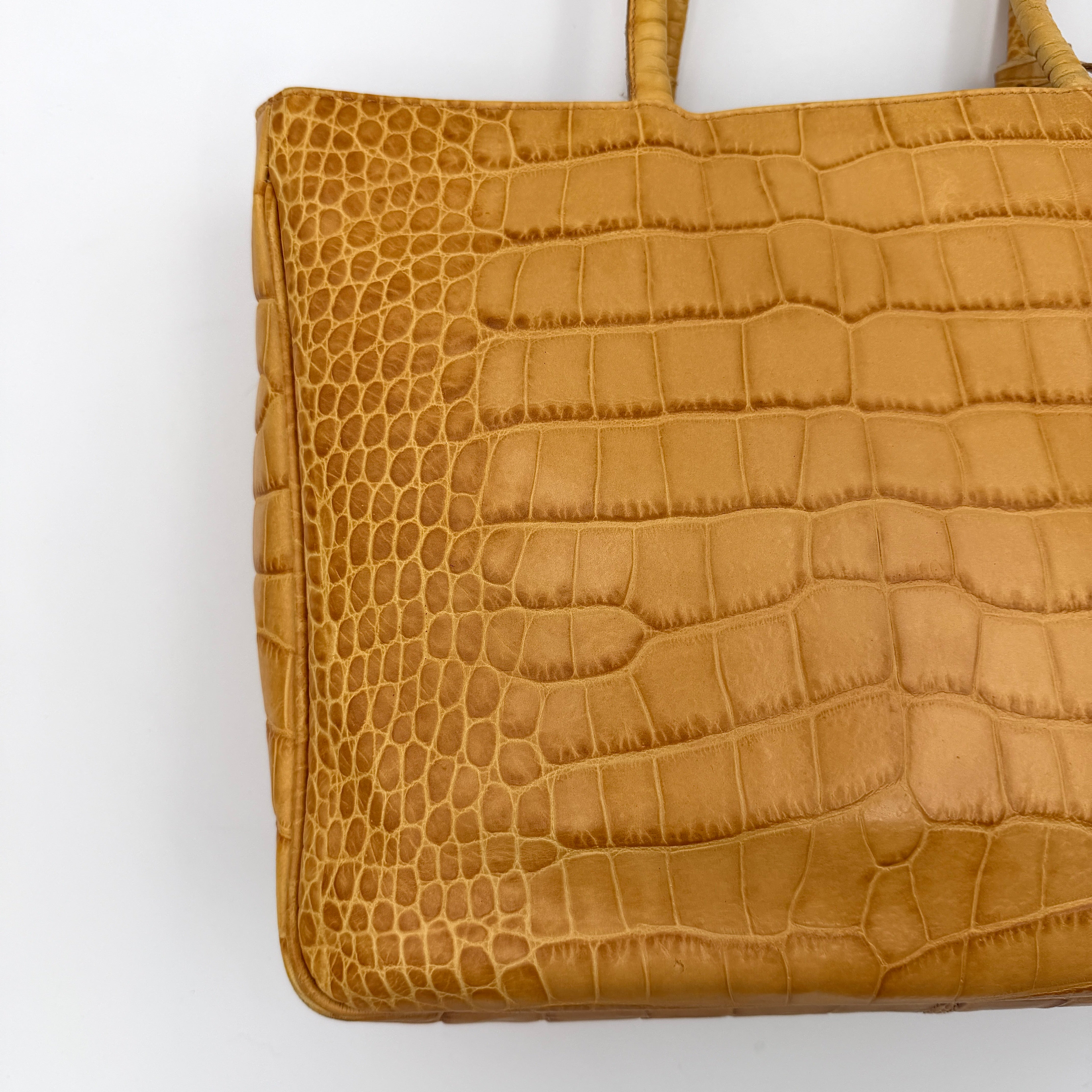 Furla yellow croc-embossed leather tote bag with double handles and matte gold logo charm, presented against a white background.