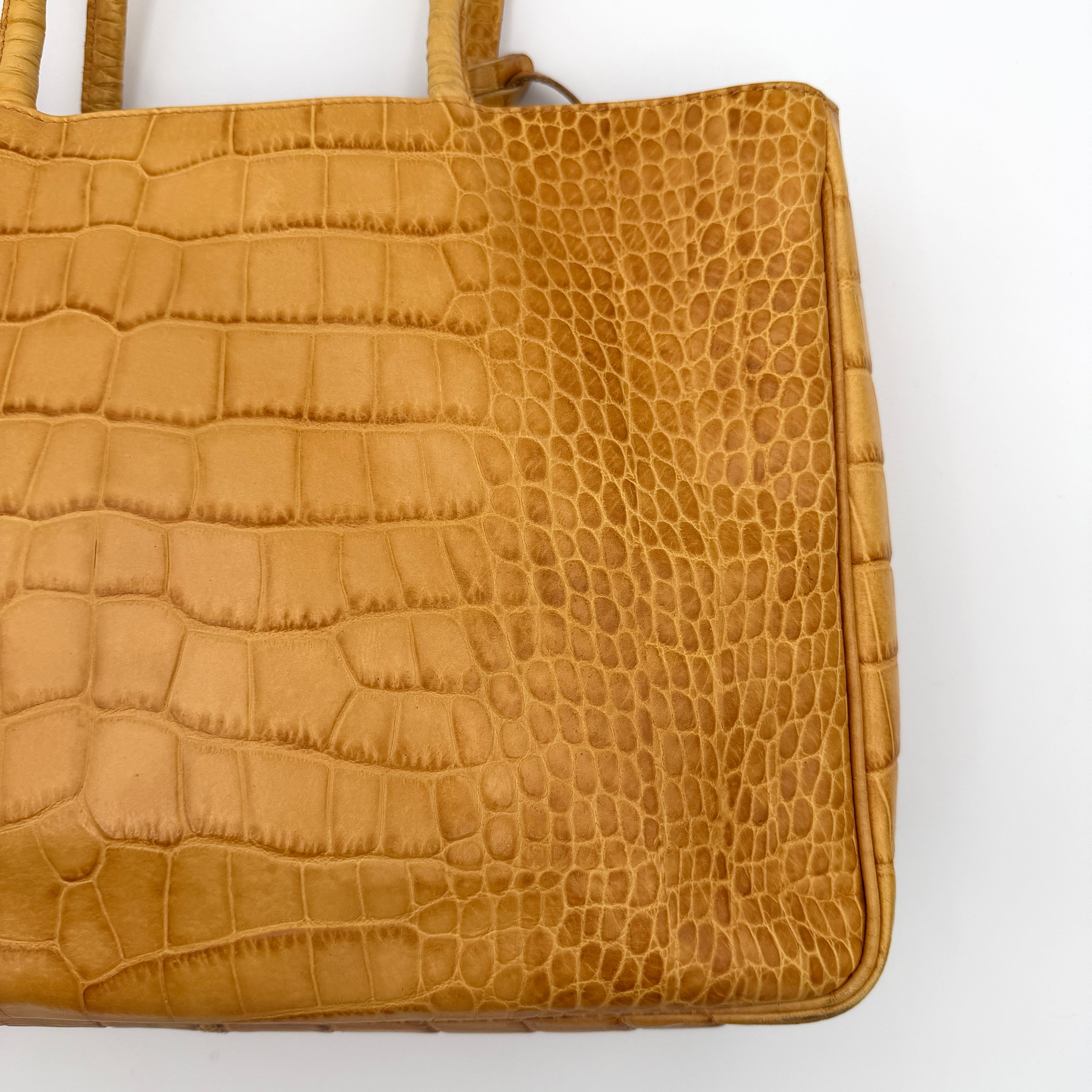 Furla yellow croc-embossed leather tote bag with double handles and matte gold logo charm, presented against a white background.
