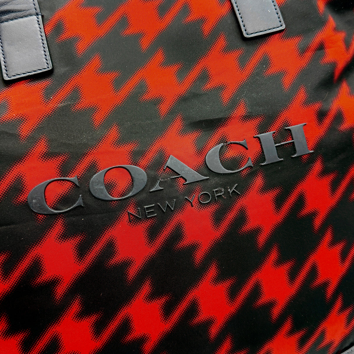 Coach Mercer Print Houndstooth Tote Bag in red and black with leather trim and handles, photographed upright against a white background.