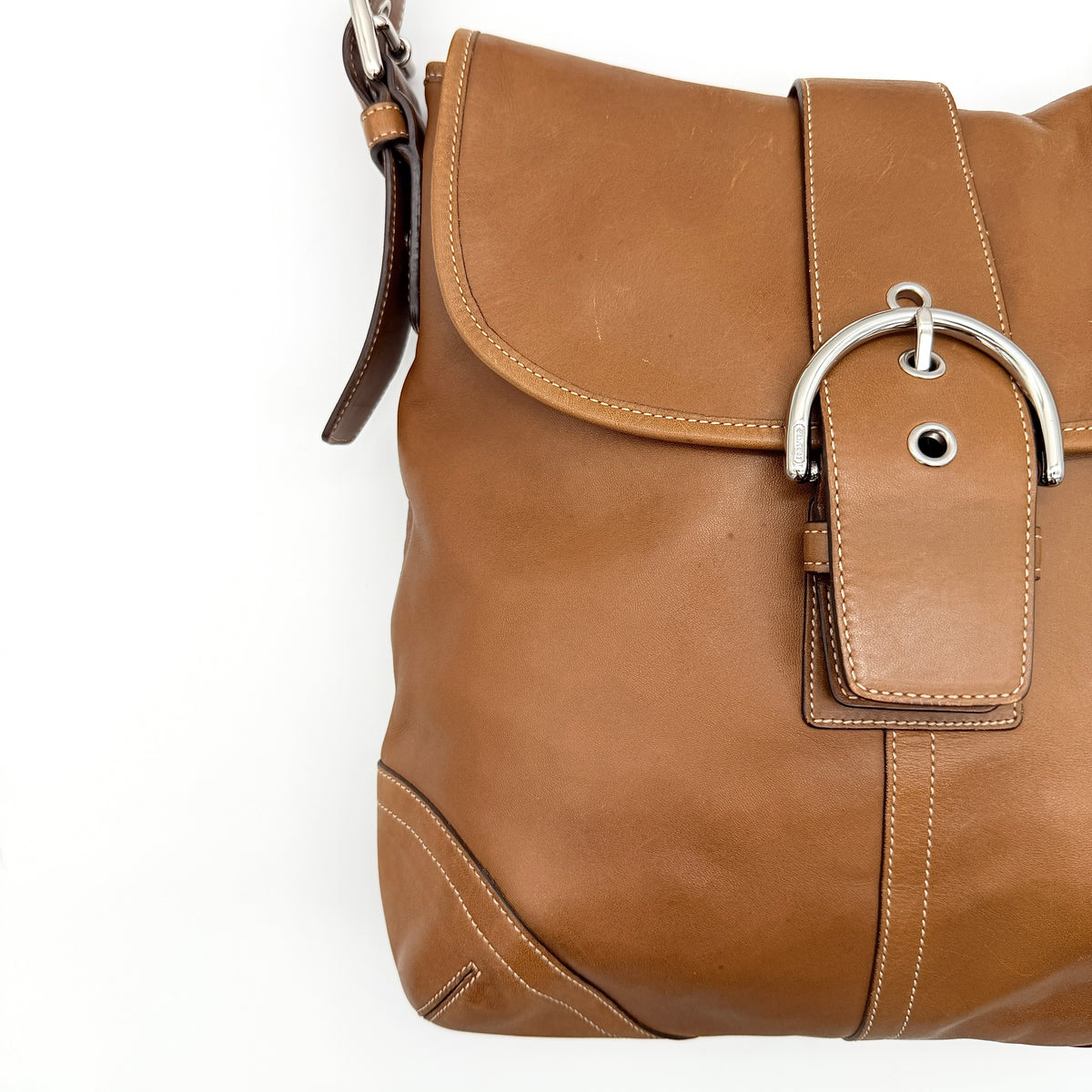 Coach Soho Buckle Flap Crossbody Bag in brown leather with buckle flap and adjustable strap, displayed on white background.