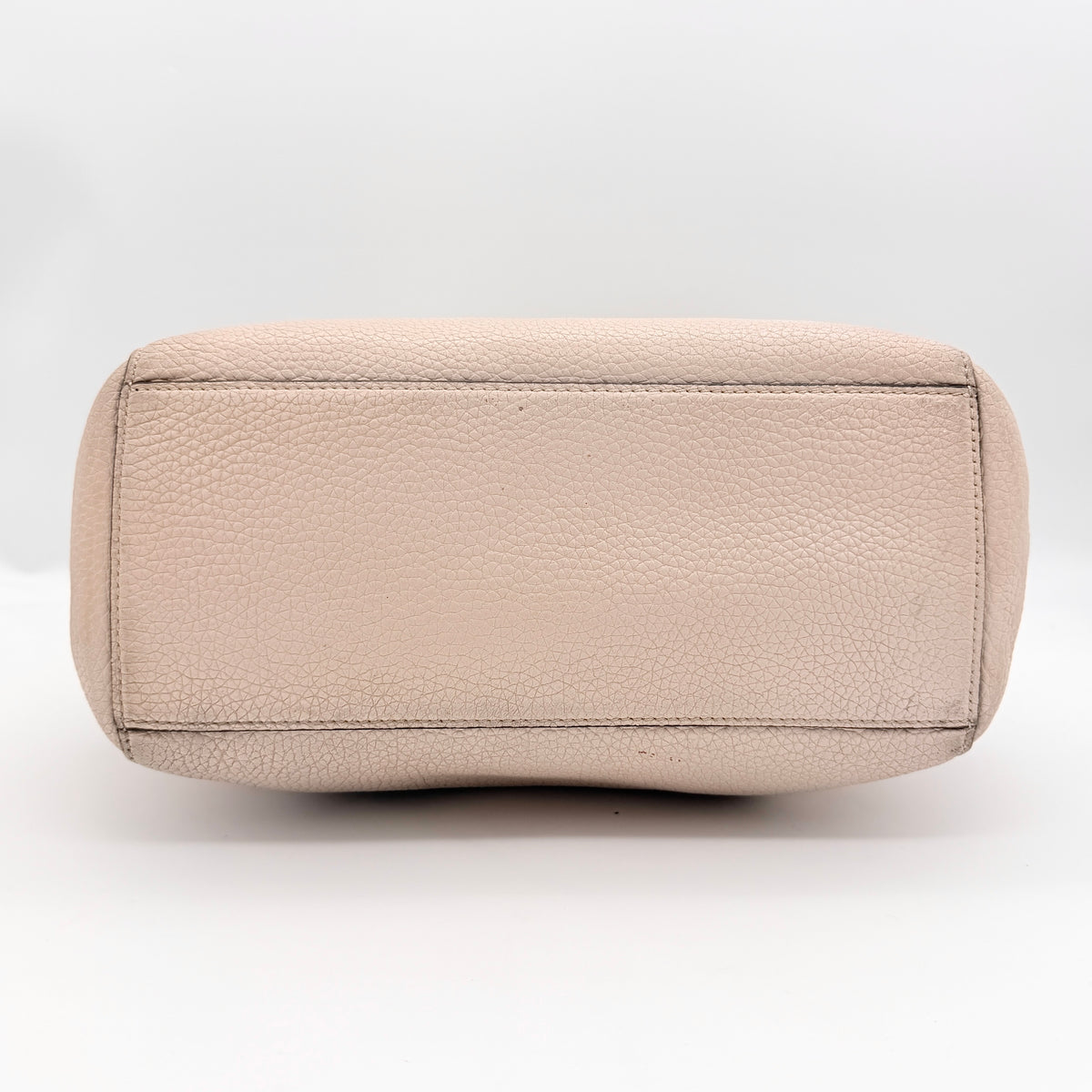 Kate Spade New York beige leather satchel with black handles, gold medallion, and grained texture against a white background.
