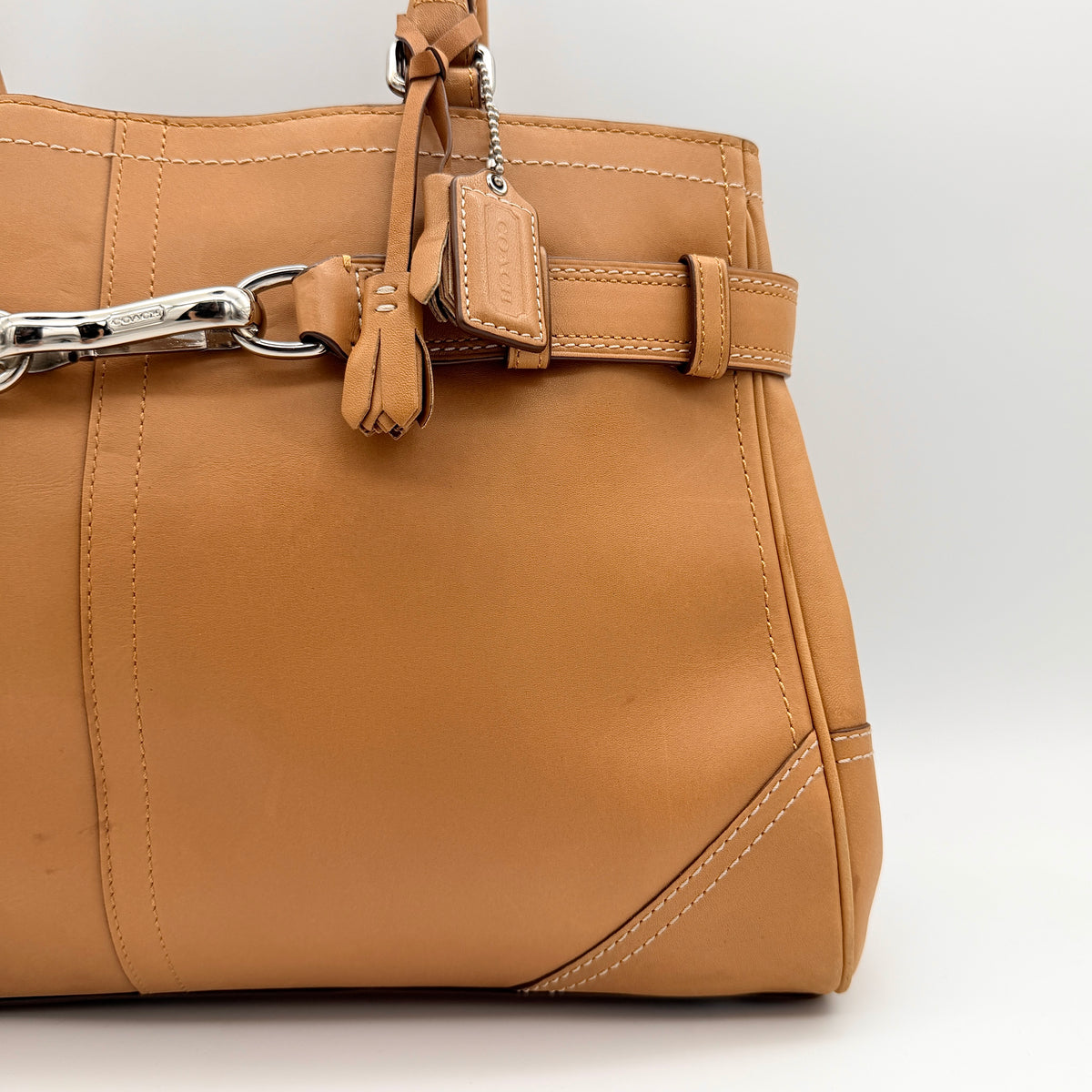 Coach Hampton Carryall in caramel brown leather with silver hardware and double handles, photographed against a white backdrop.