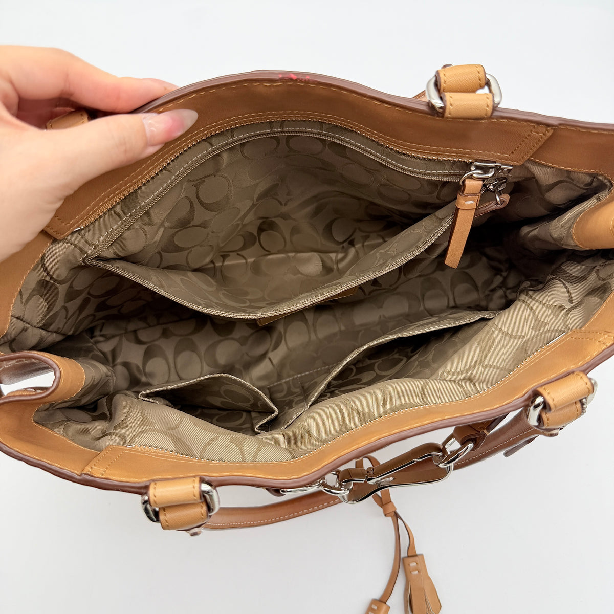 Coach Hampton Carryall in caramel brown leather with silver hardware and double handles, photographed against a white backdrop.